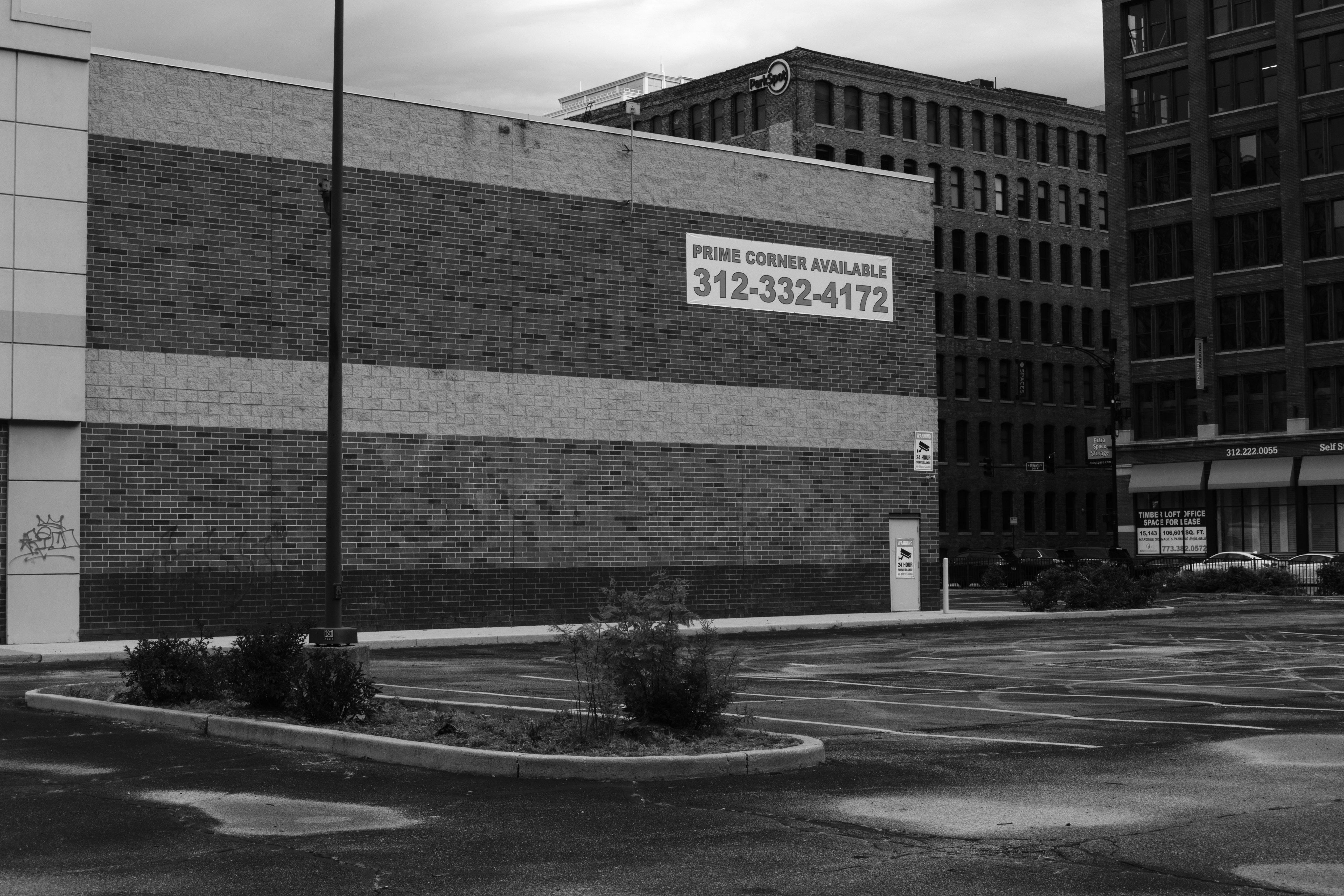 Urban building with "for lease" sign and vacant parking lot.