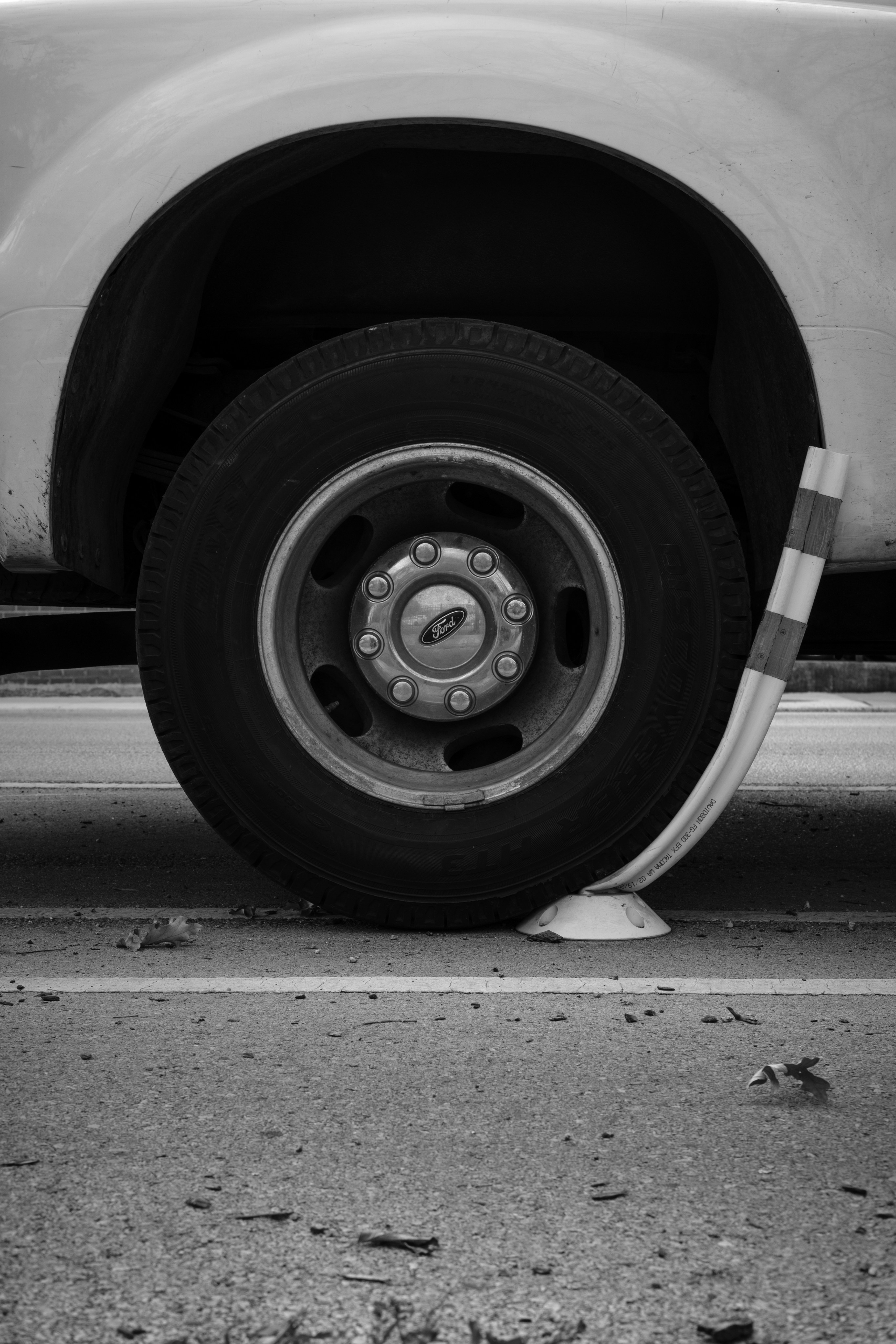 Truck wheel parked beside a bent striped traffic bollard.