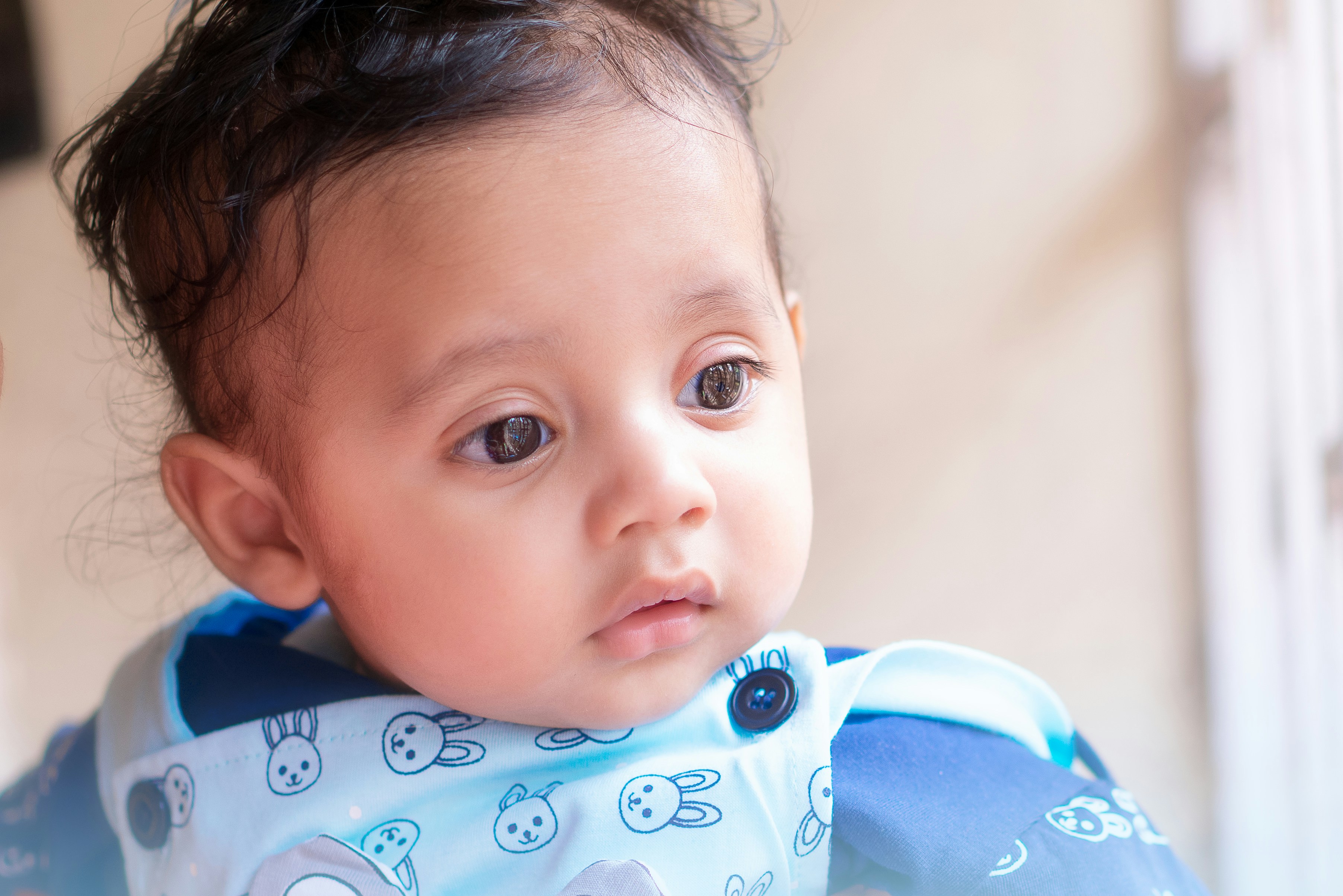 A cute baby with curly hair wearing a bunny bib.