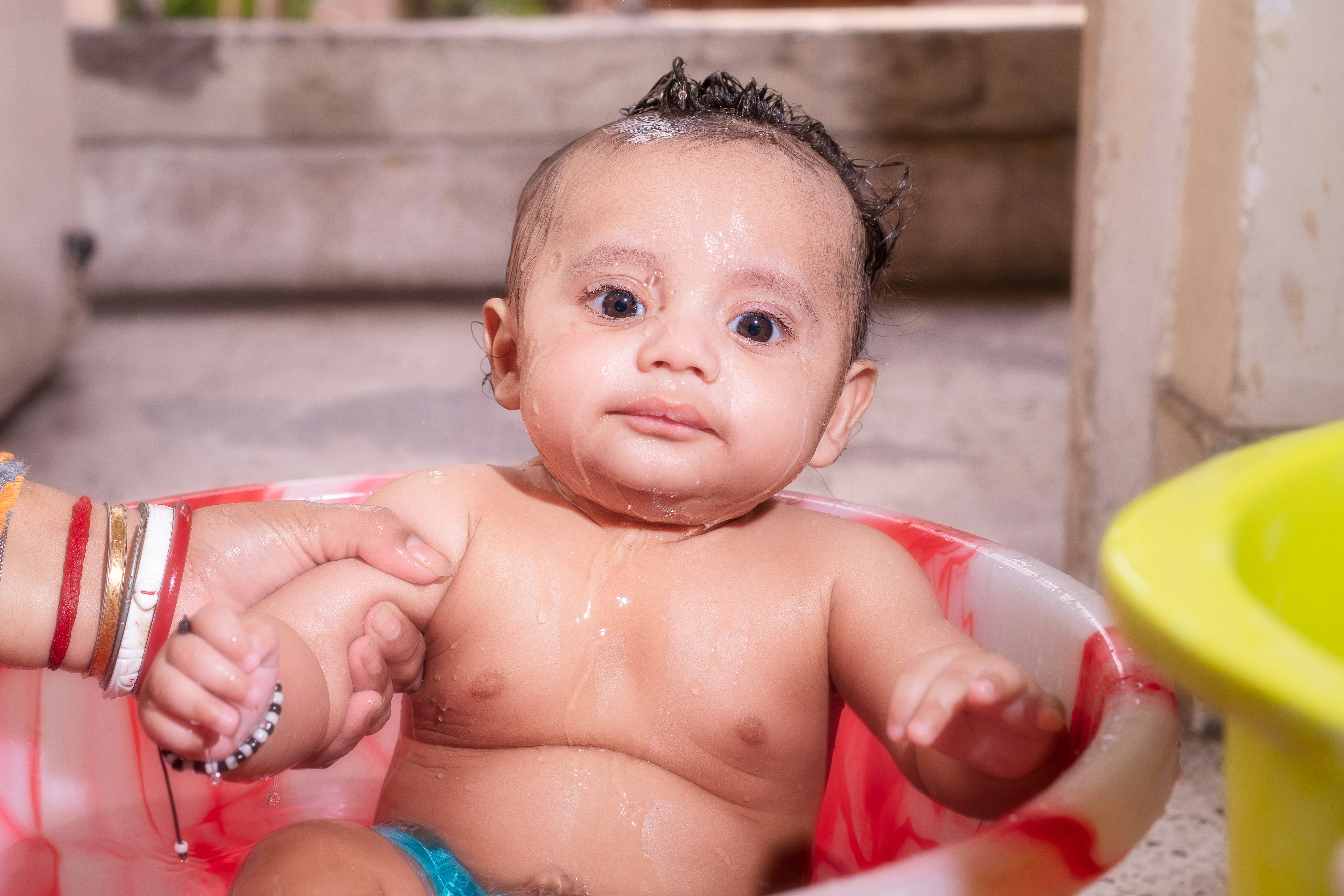 Adorable baby getting a bath in a small tub.