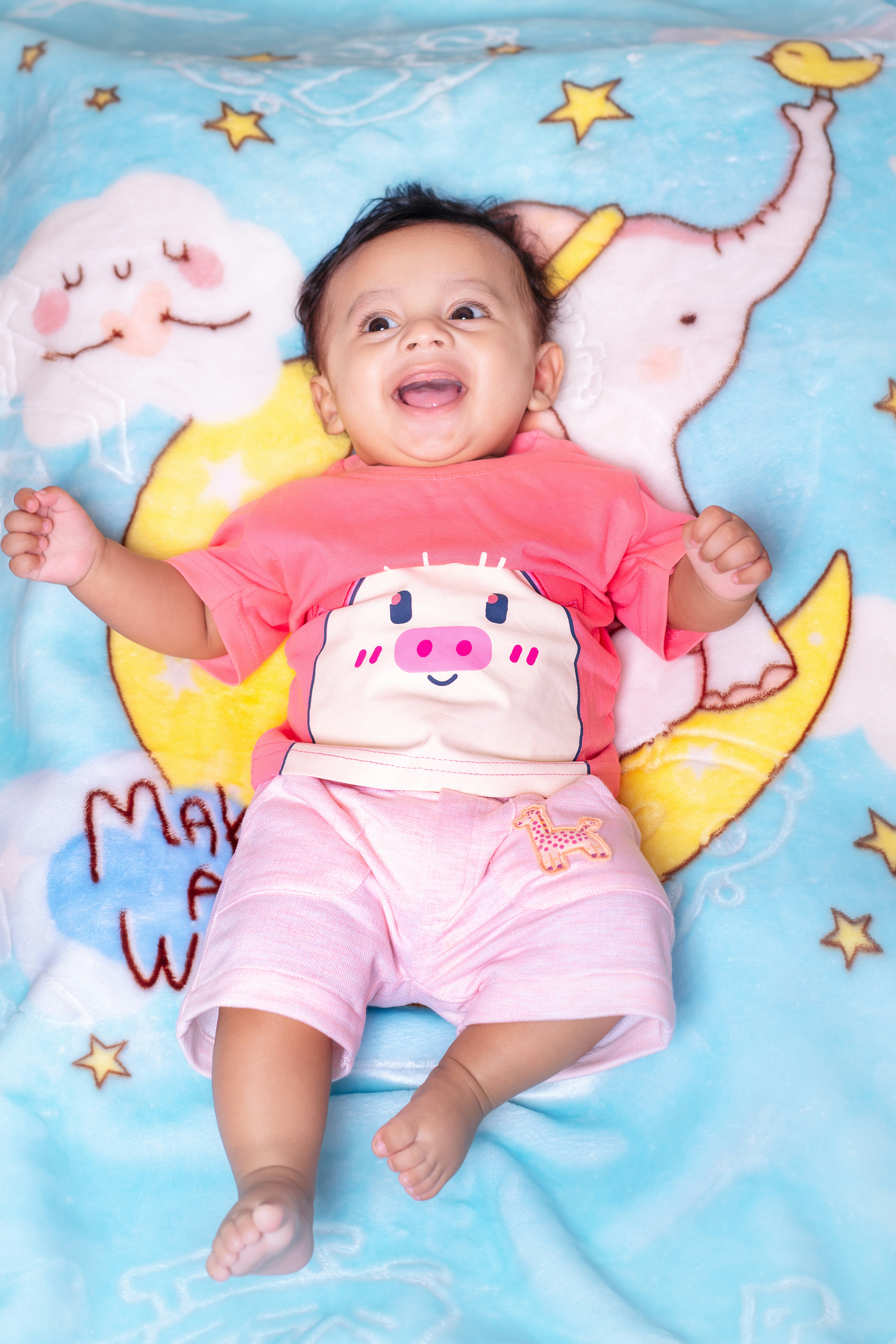 Happy baby lying on a blue cartoon blanket.