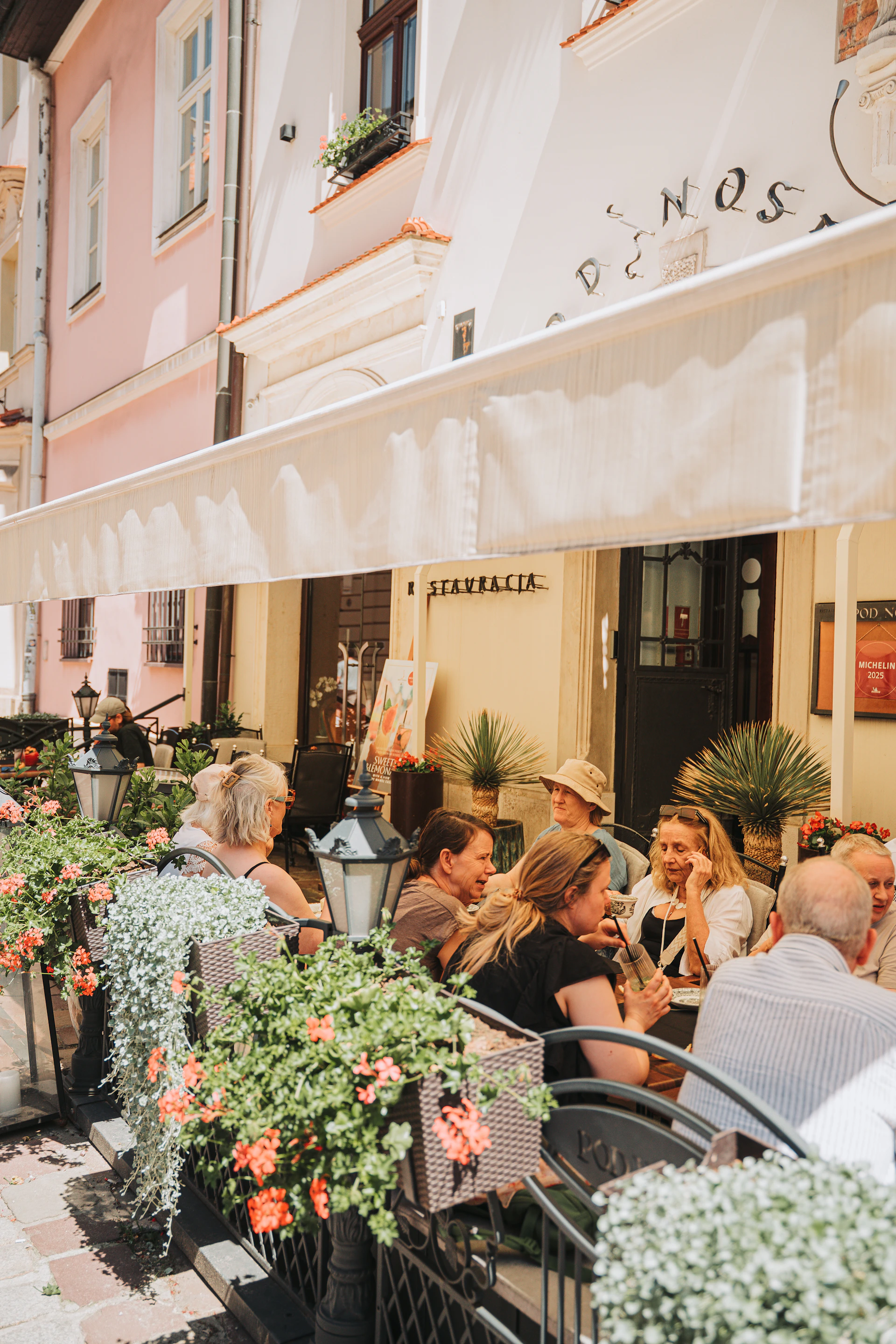 People enjoy drinks at an outdoor cafe with flowers.