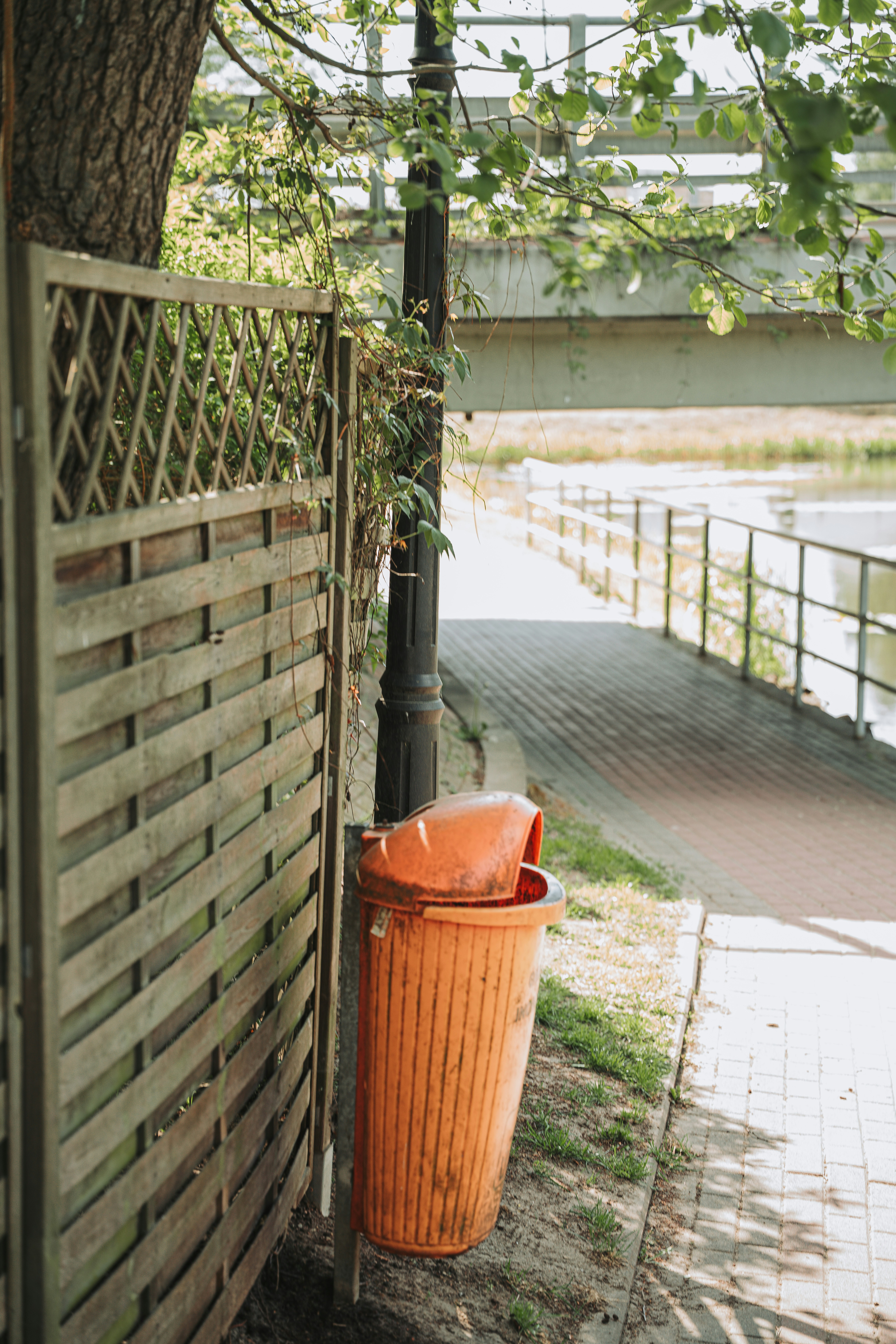 Oranger Mülleimer am Holzzaun, Weg und Brücke