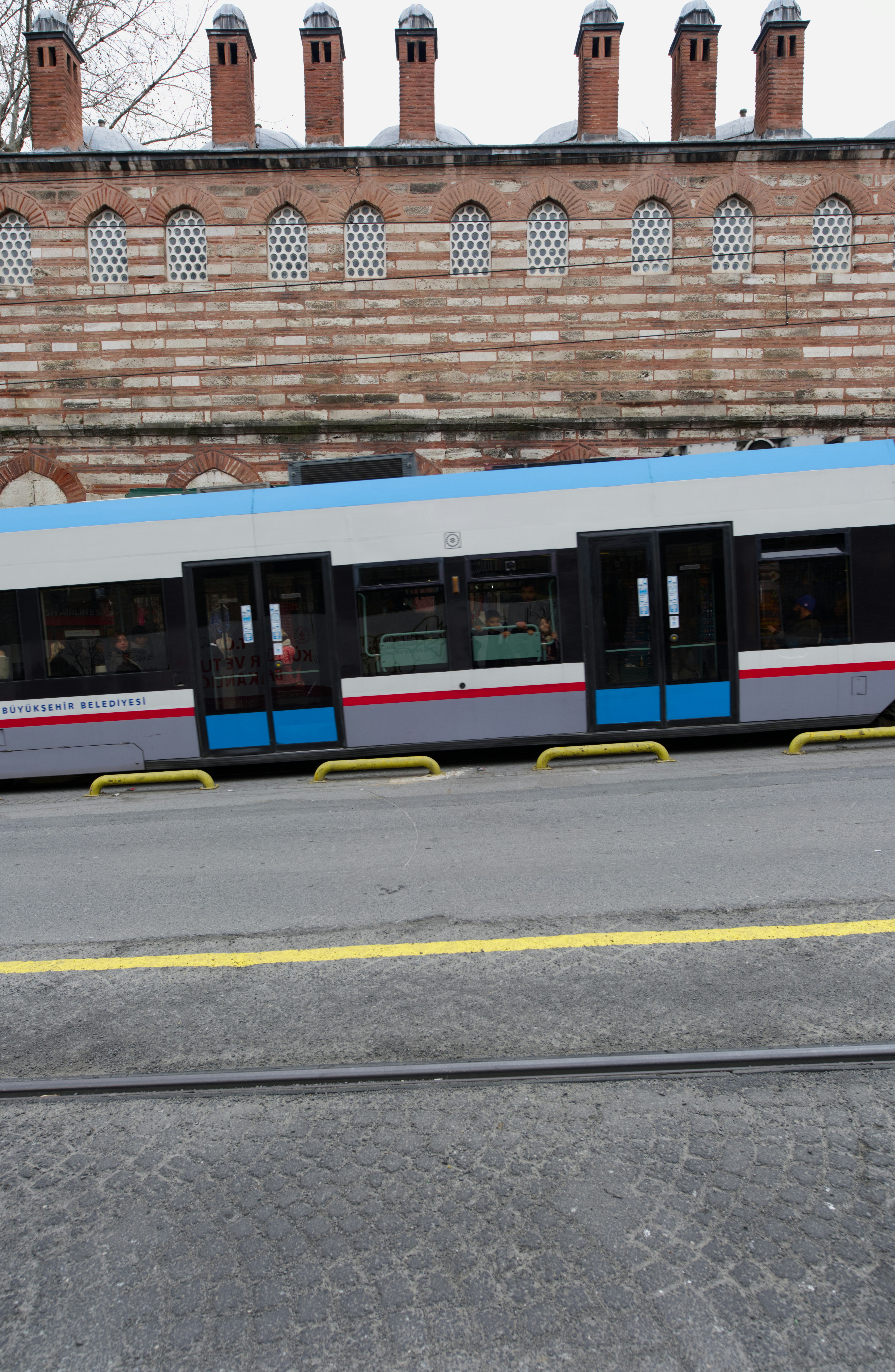 Un tram blu passa davanti a un edificio storico in mattoni.
