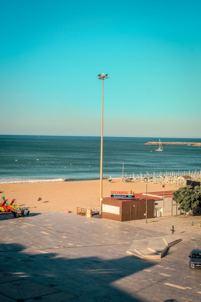 Sunny beach with a tall lamppost and a blue ocean
