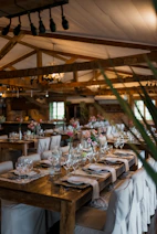 Rustic dining hall with elegantly set wooden tables and flowers