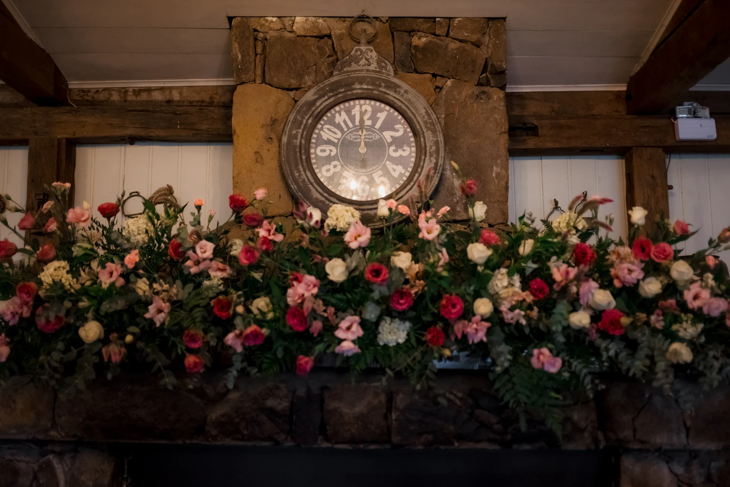 Vintage clock surrounded by romantic flowers on a stone mantel