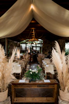 Rustic wedding ceremony setup with pampas grass and draped ceiling