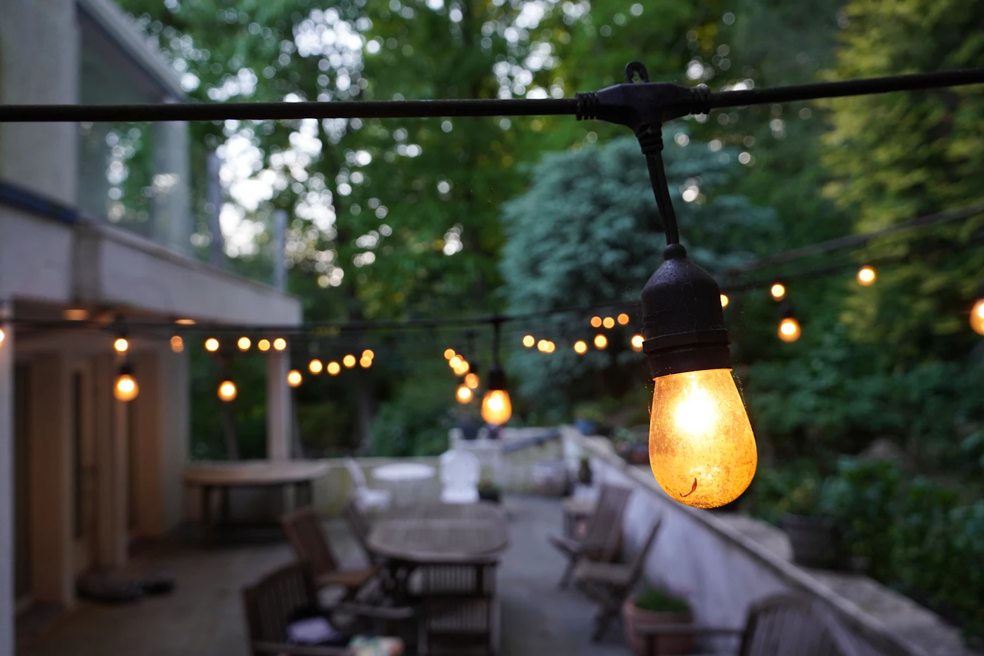 Budget-friendly rehearsal dinner ideas — String lights illuminate a casual backyard rehearsal dinner setup.