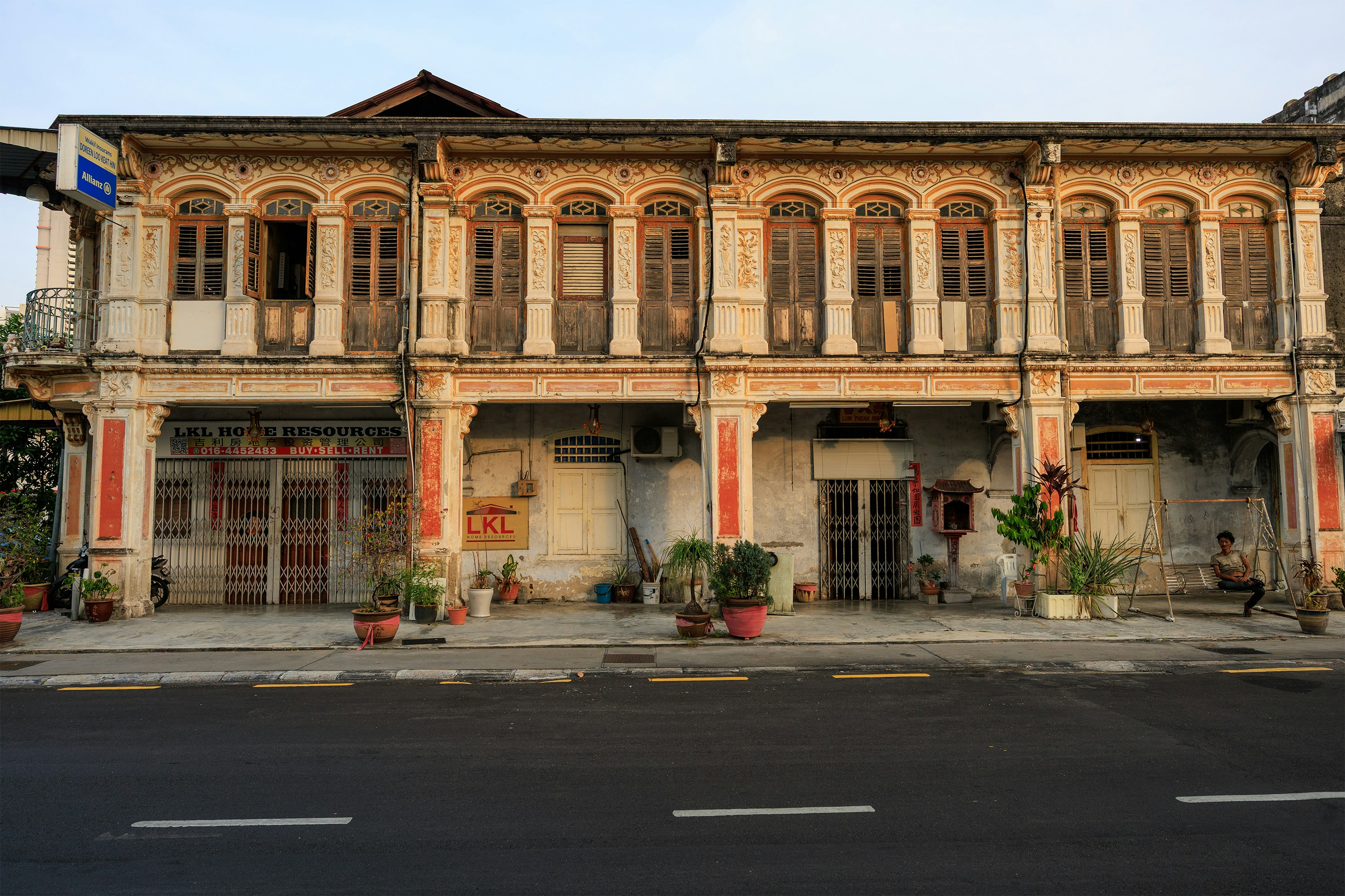 Historic shophouses with ornate facades along a quiet street.