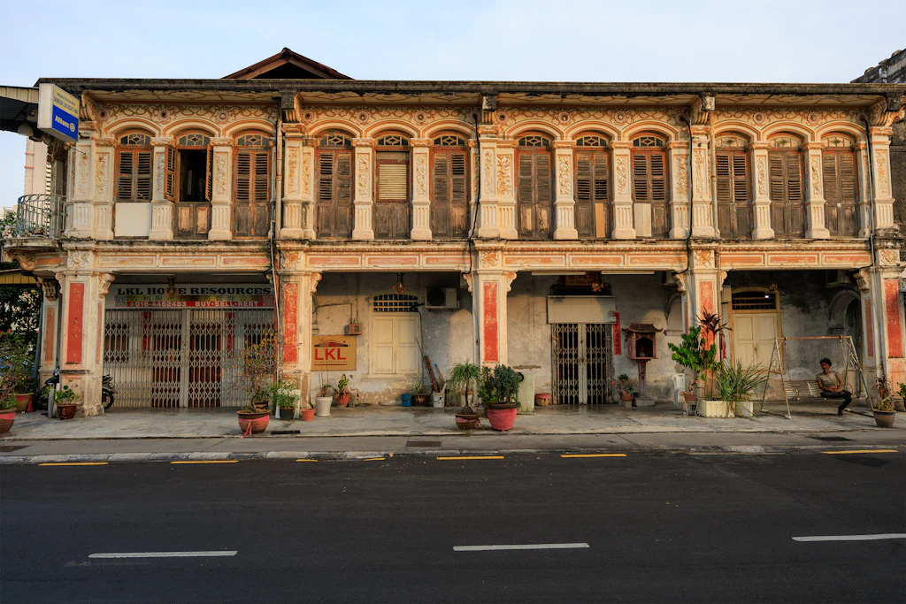 Weathered two-storey heritage shophouses with carved facades on a quiet George Town street