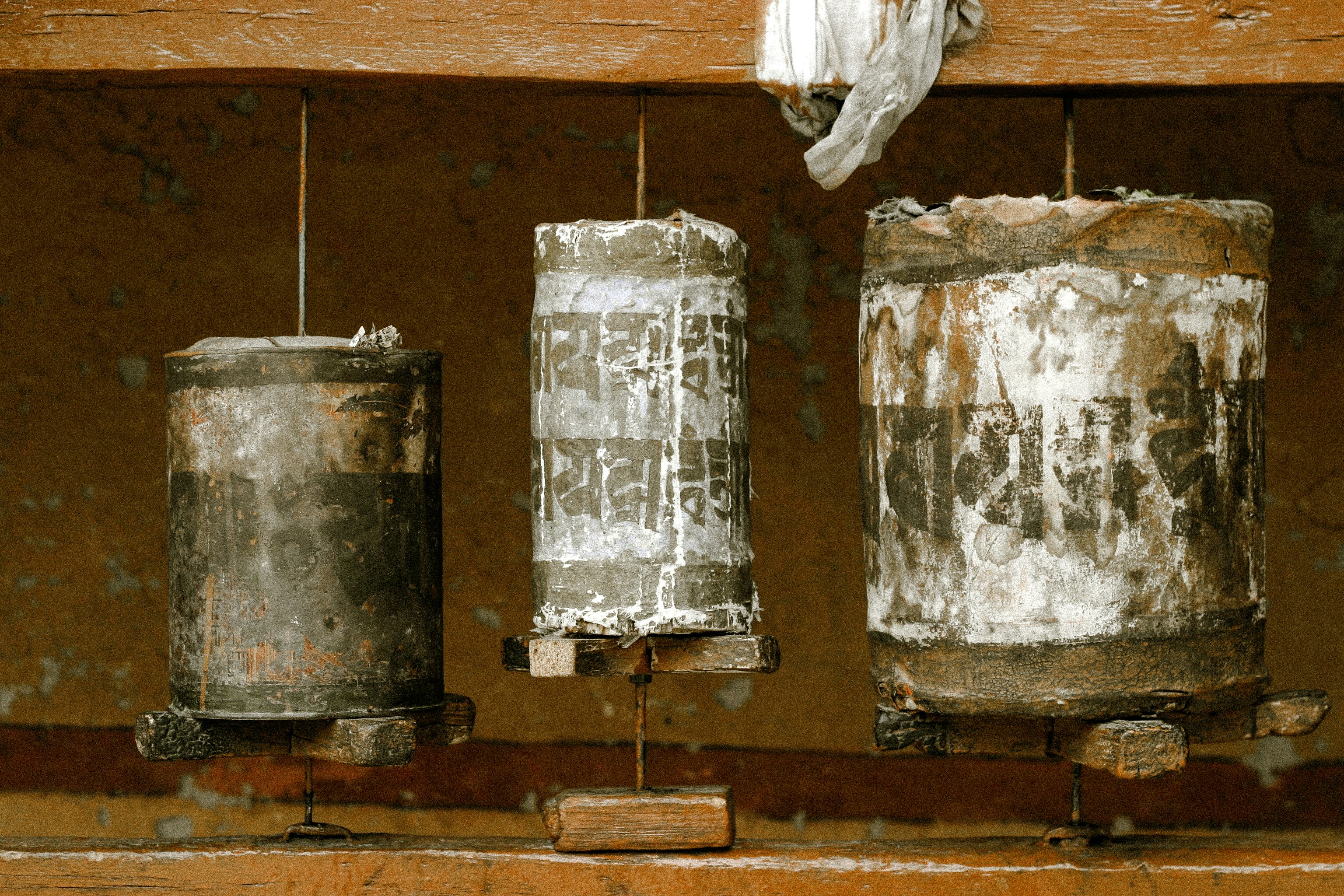 Three rustic prayer wheels hanging in a row