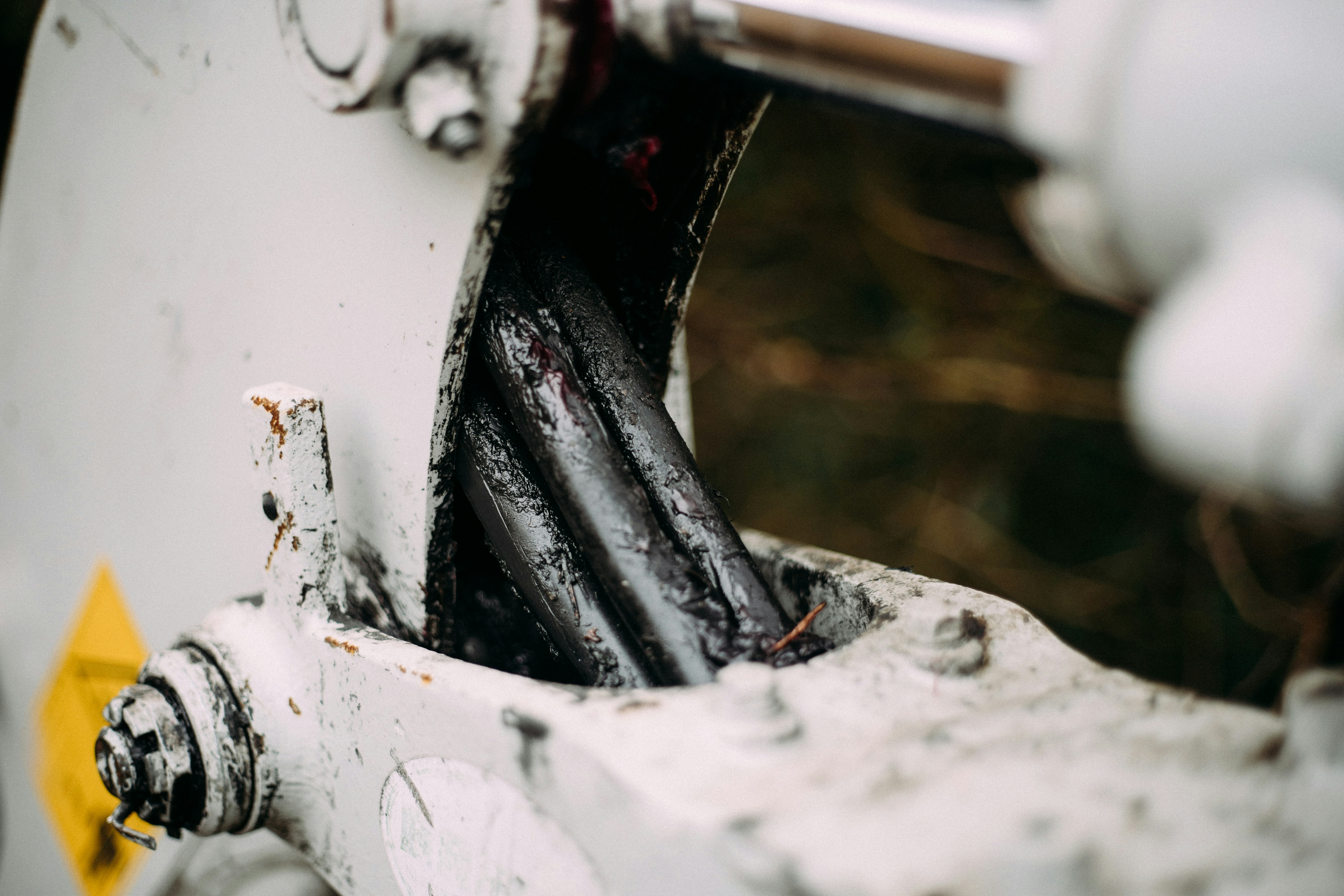 Worn cables and hydraulic cylinder on heavy machinery.