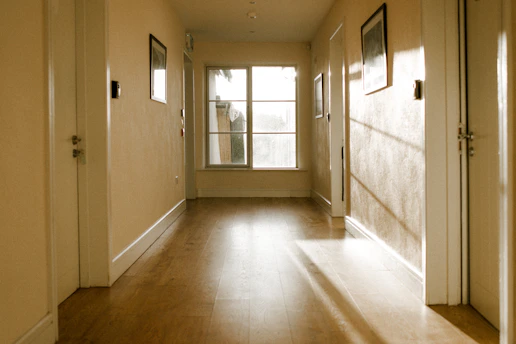 Bright sunlight illuminates a long, empty hallway with a window.