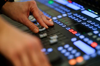 A hand adjusts controls on a professional audio mixing console