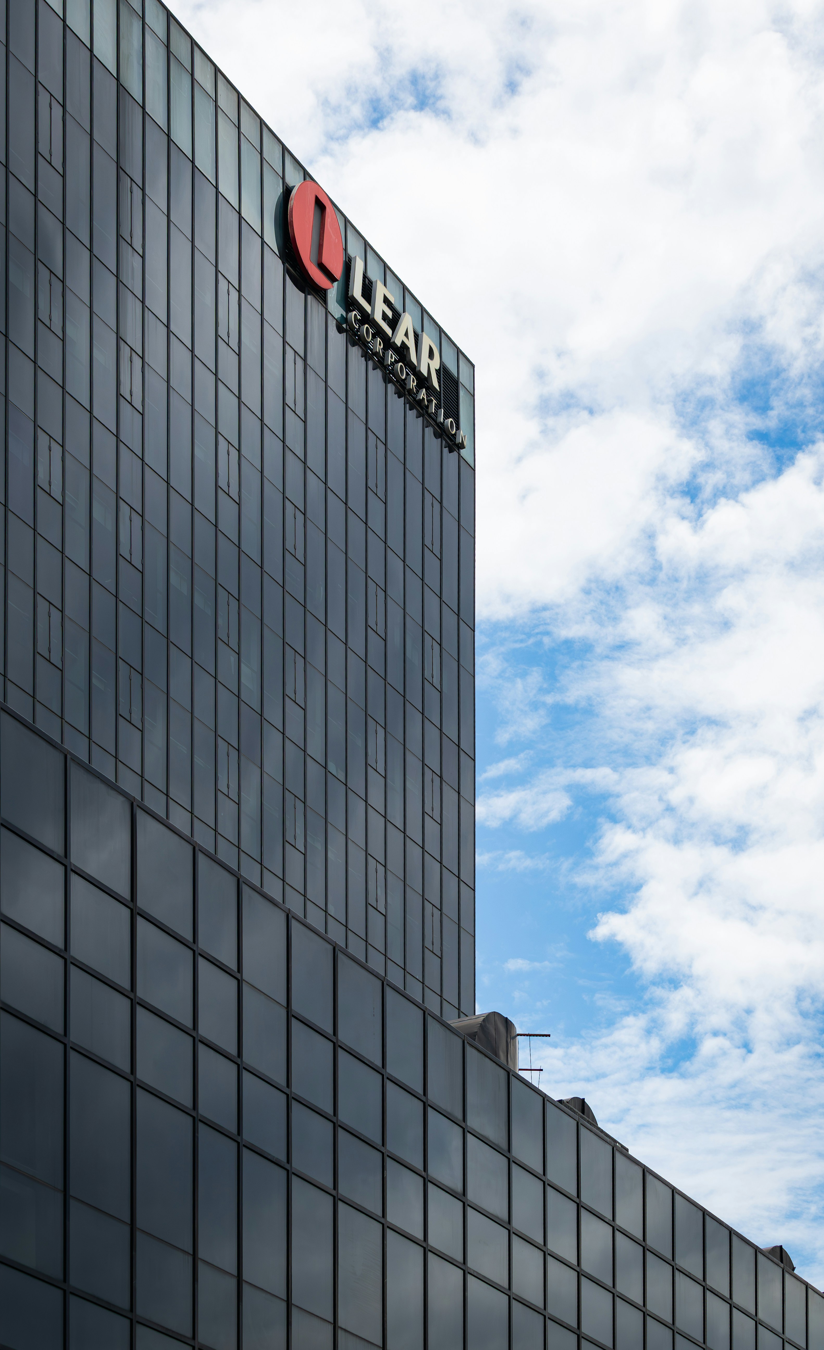 Modern glass building with lear corporation logo against blue sky.