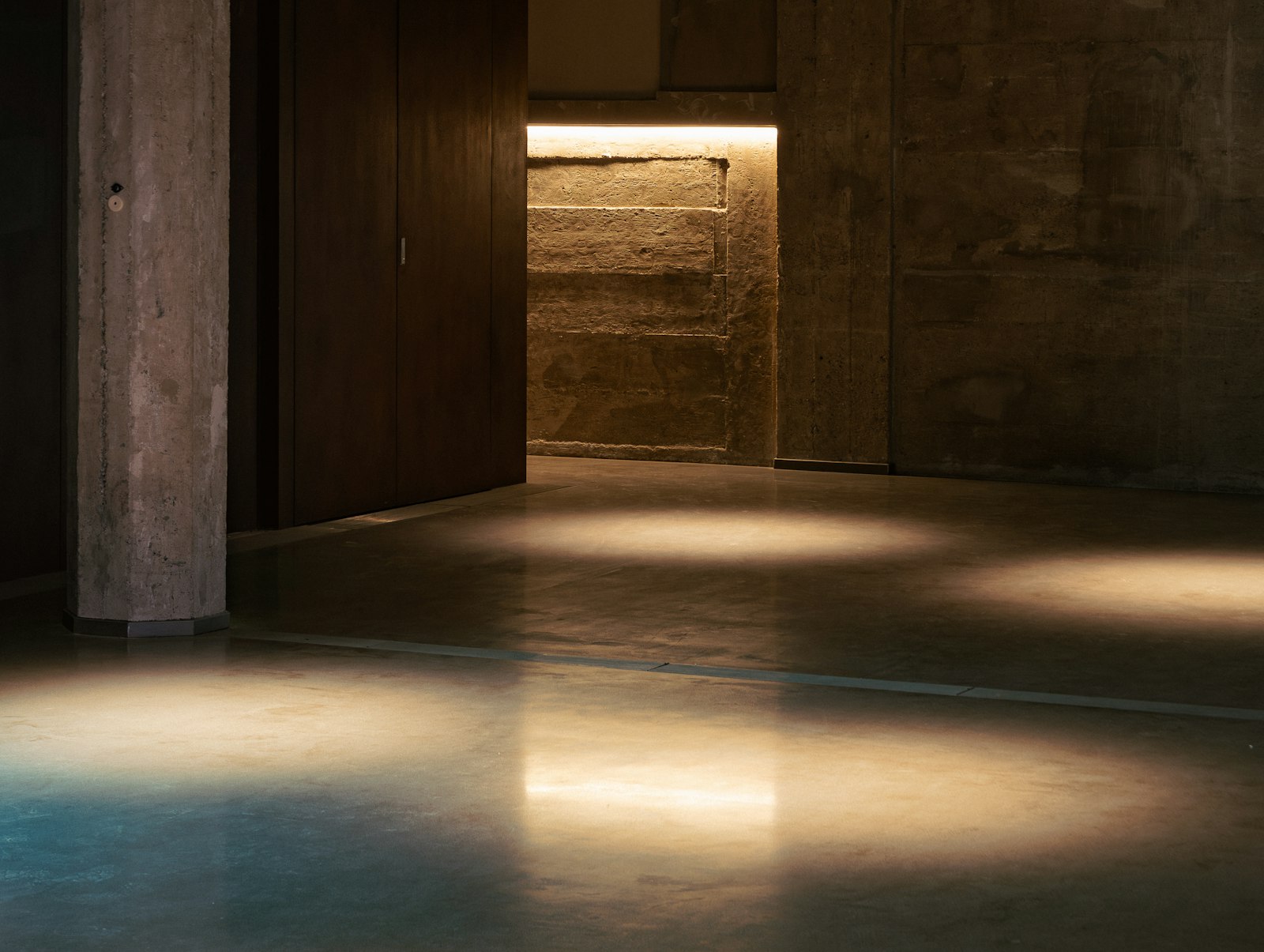 Board-formed concrete wall lit with warm light