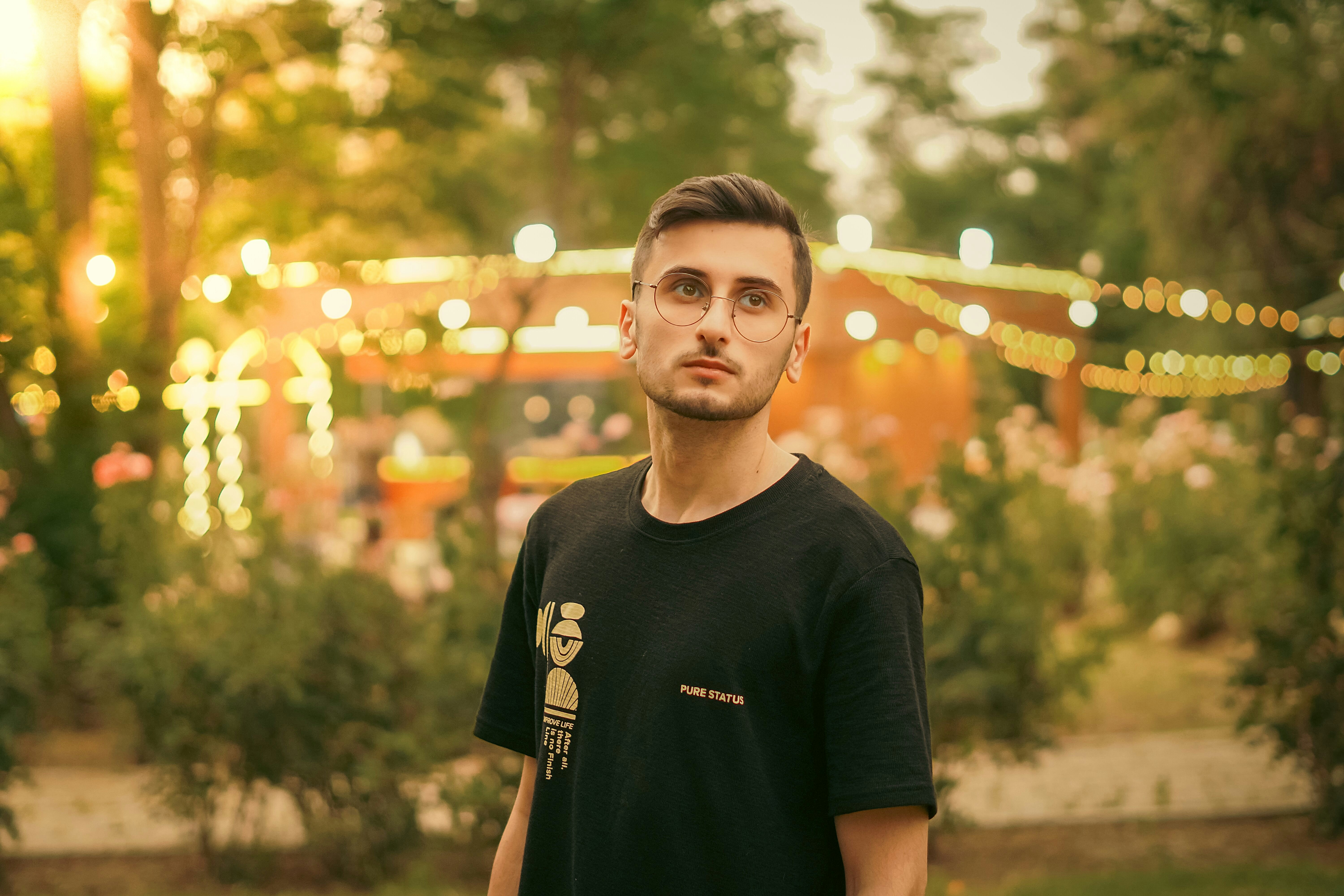 Man in black shirt standing outdoors with bokeh lights