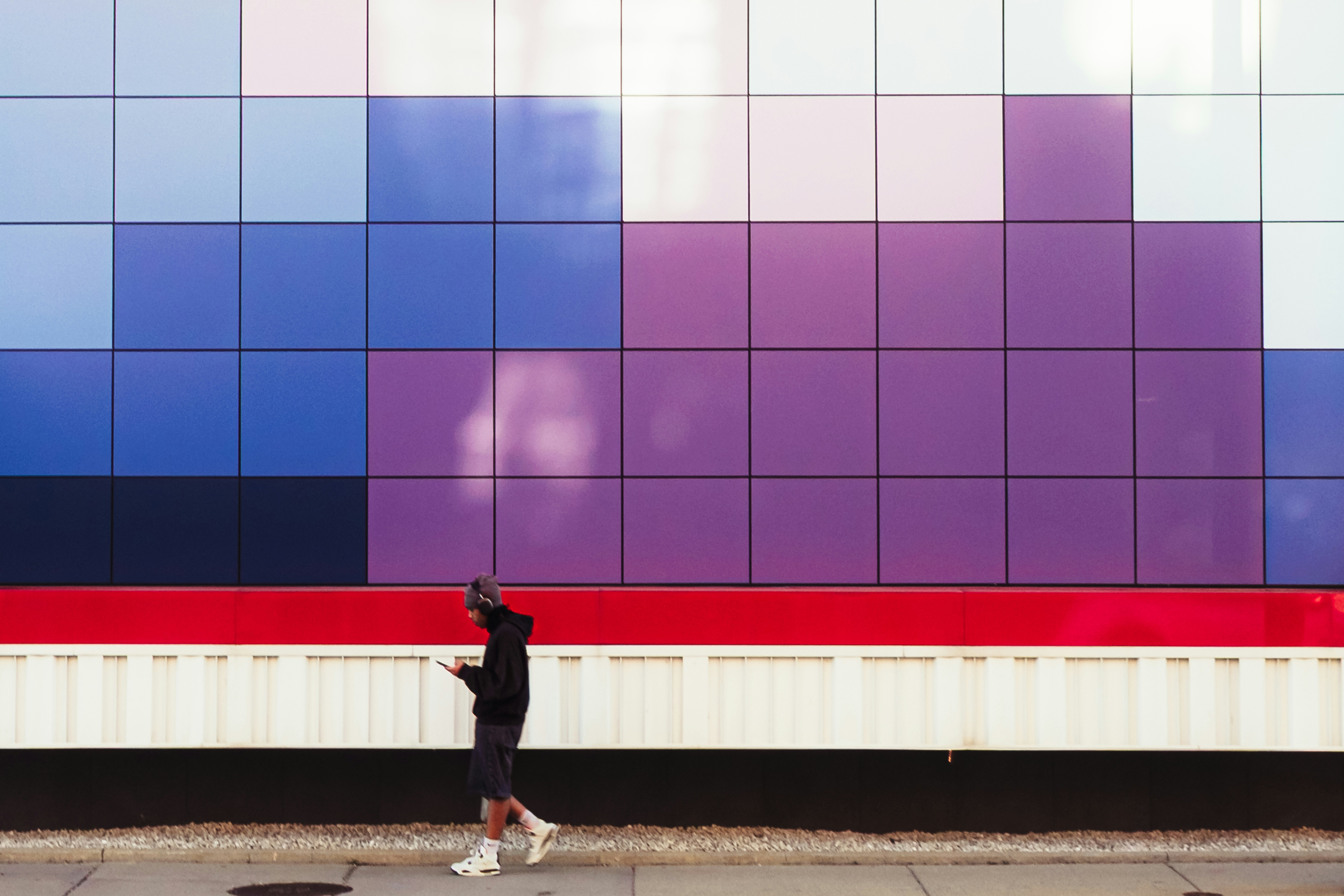Una persona pasa junto a una pared de mosaico colorido.
