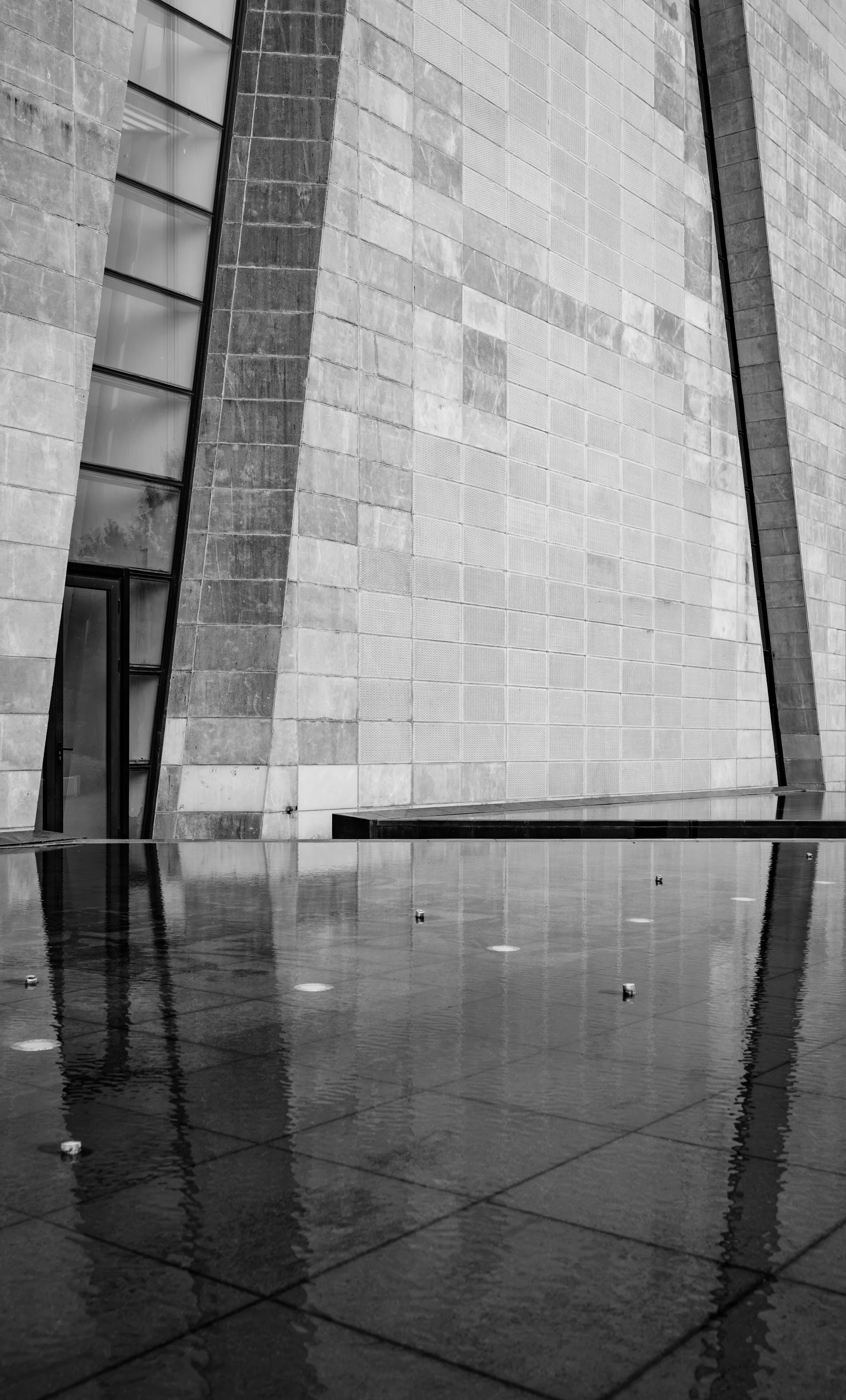 Textured building wall reflecting in still water