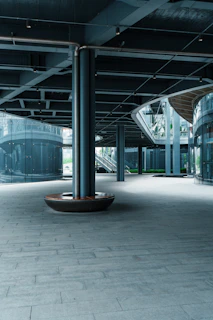 Modern urban walkway with large support pillars and glass buildings.