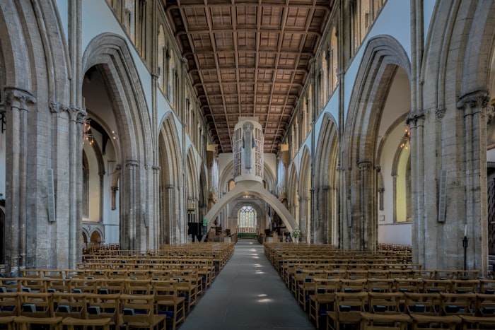 Nave central de una iglesia con arcos góticos y pasillo central, ambiente solemne