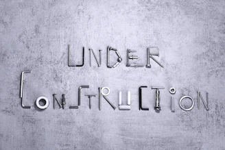 Under construction spelled with metal hardware on a gray background.