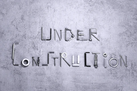 Under construction spelled with metal hardware on a gray background.