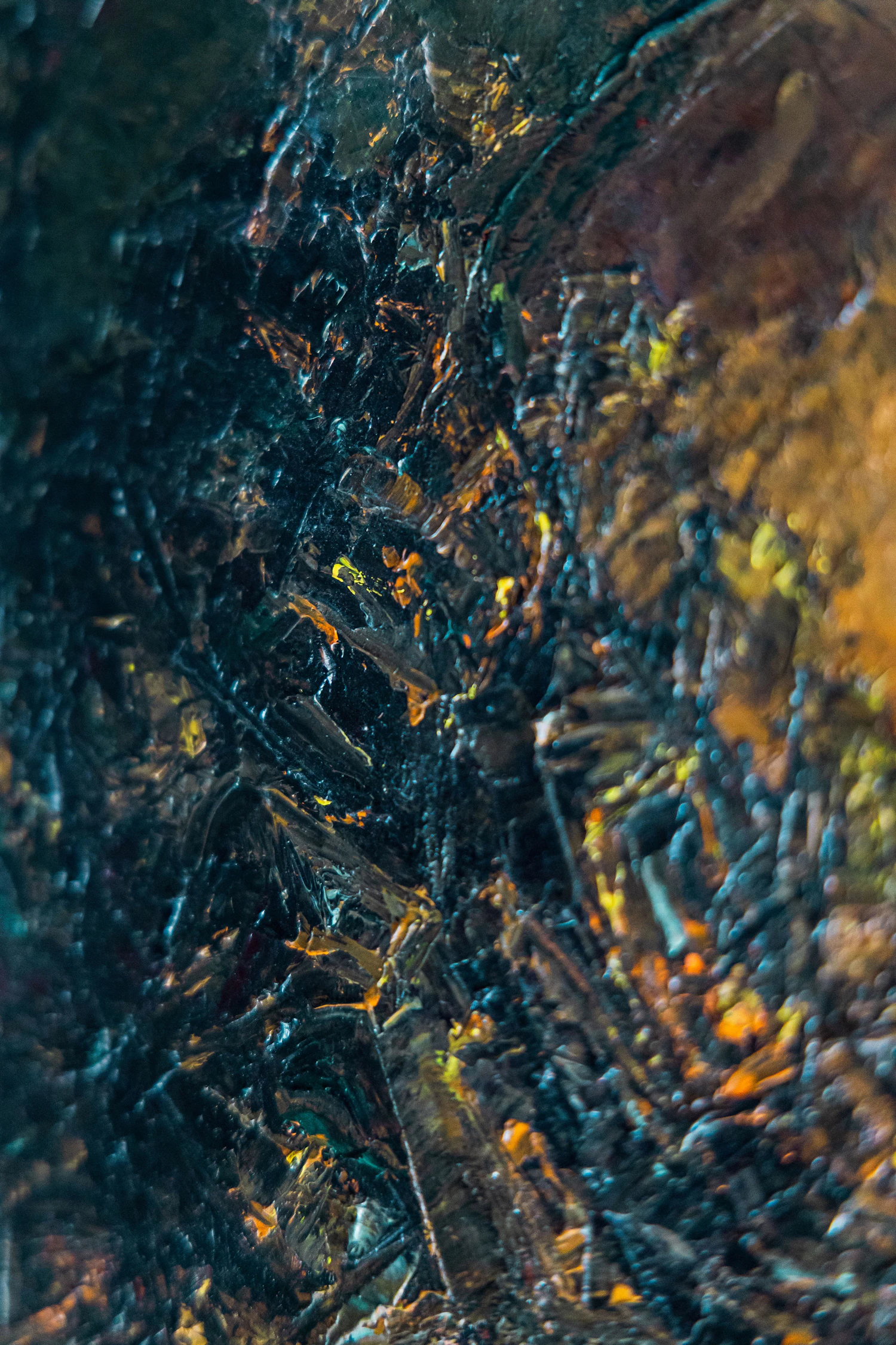 A dark abstract painting built from heavy blue and orange impasto