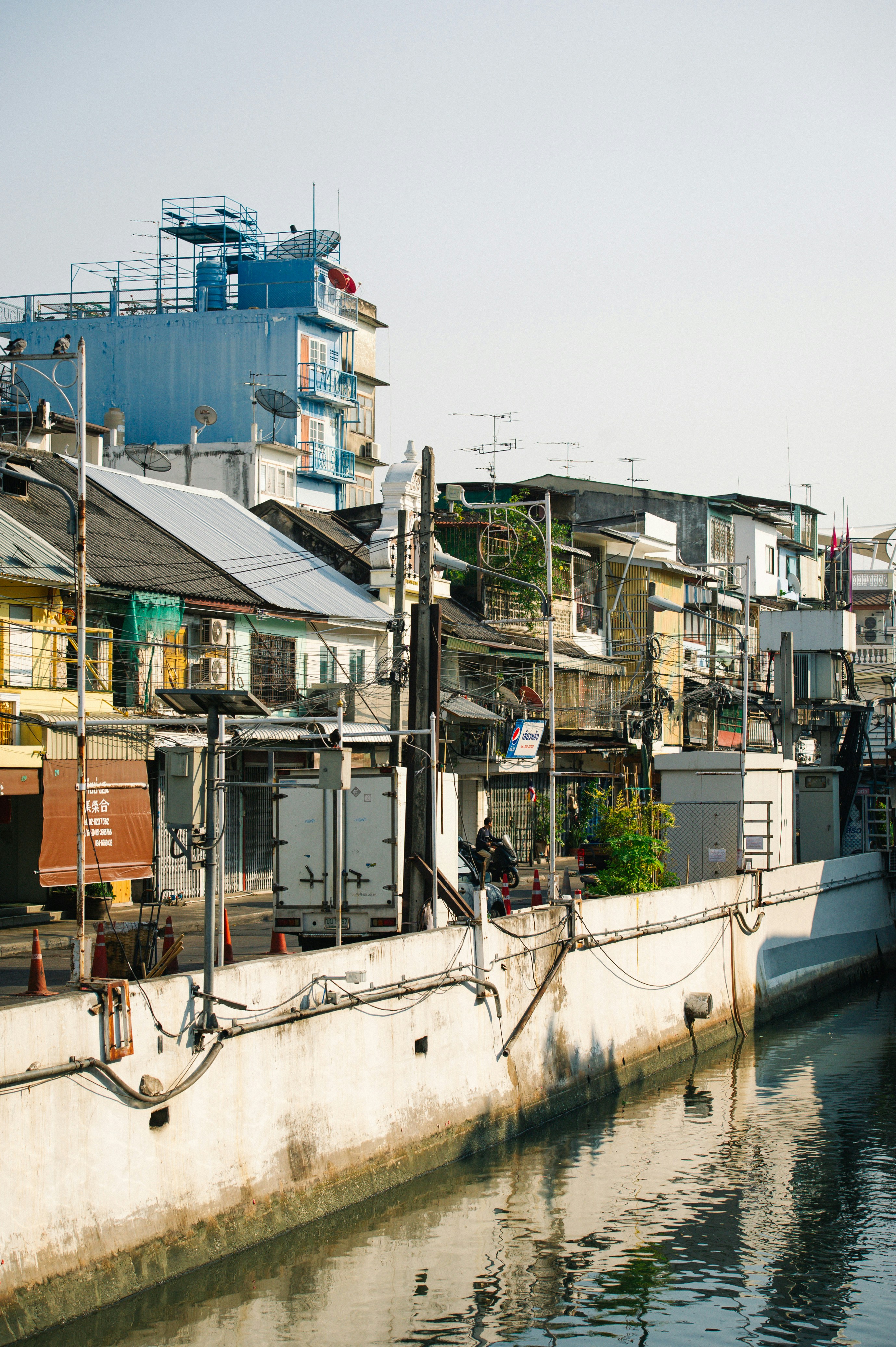 Old buildings line a narrow canal under a clear sky.