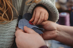 Adult and child hands holding fabric pieces together.