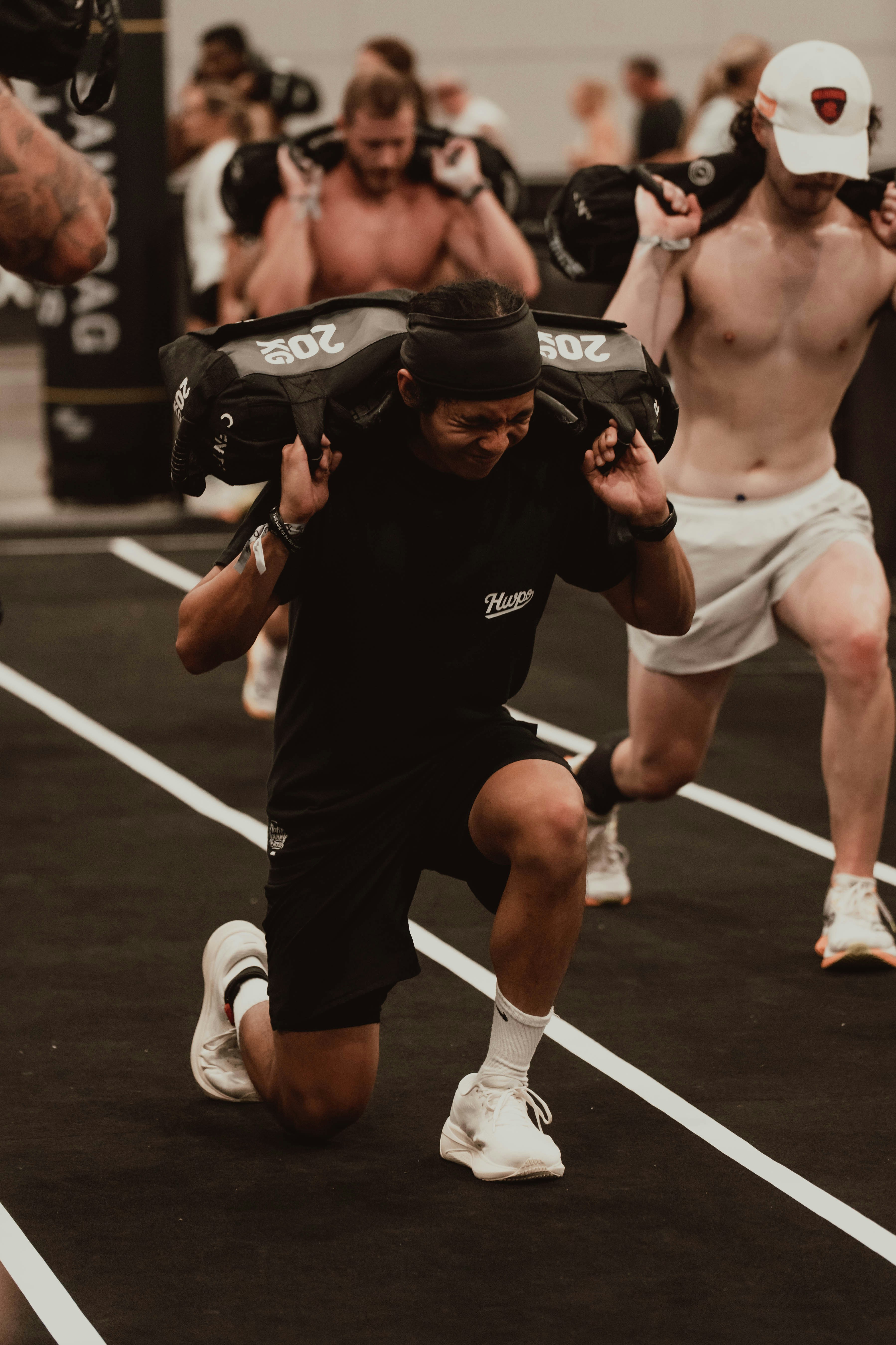 Man performing lunges with a heavy sandbag in a gym