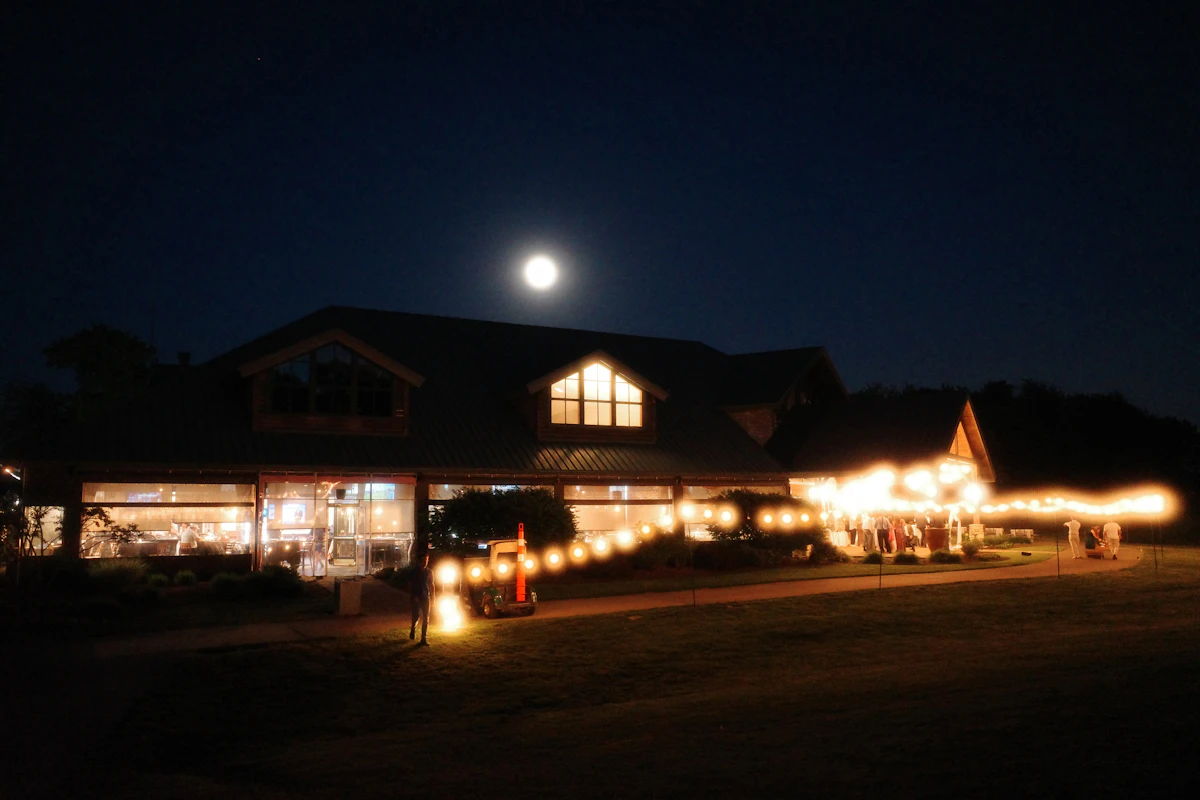 A reception marquee glowing against a deep blue evening sky
