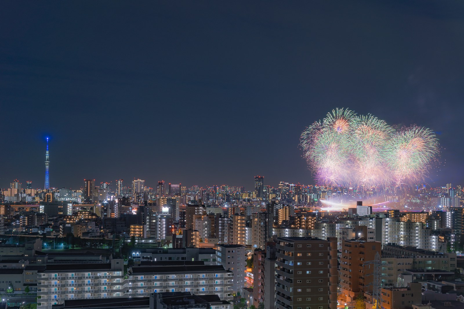 Fireworks blooming above the Tokyo skyline with Tokyo Skytree visible at night
