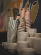 Stacks of colorful paper cups and white ceramic bowls.