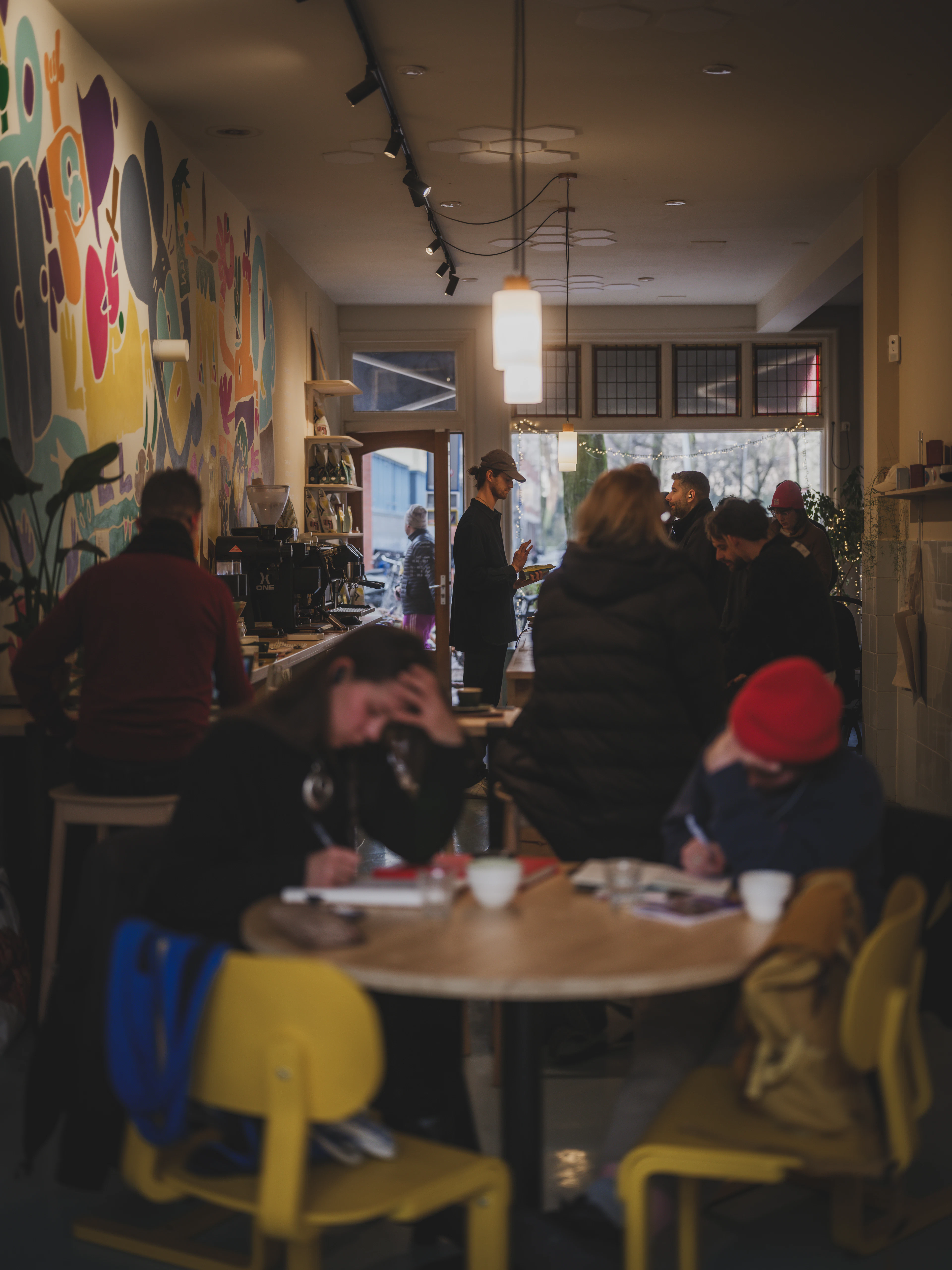 A crowd gathered in a café with bright wall art