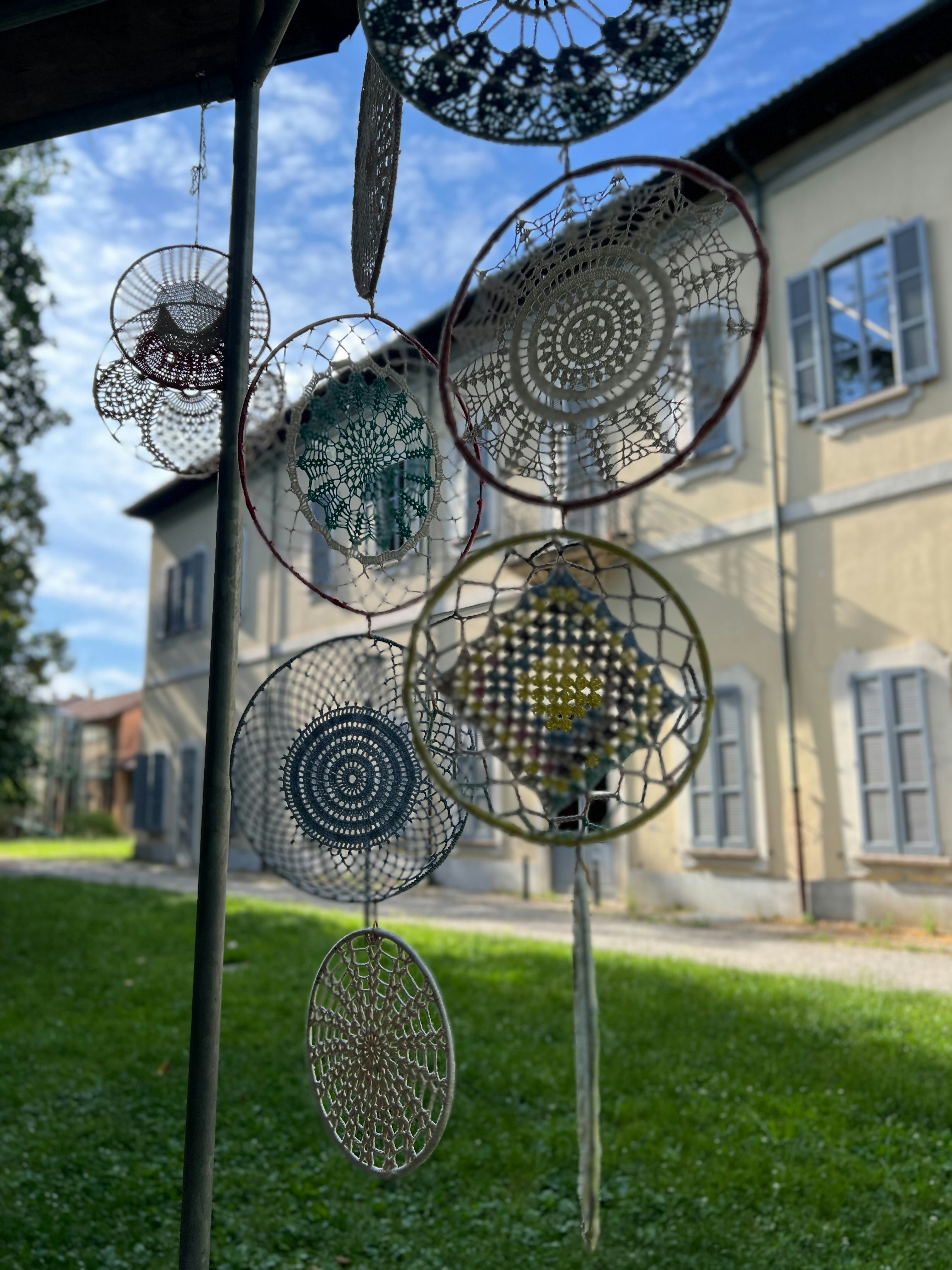 Intricate decorazioni circolari intrecciate sospese all'aperto vicino a un edificio.