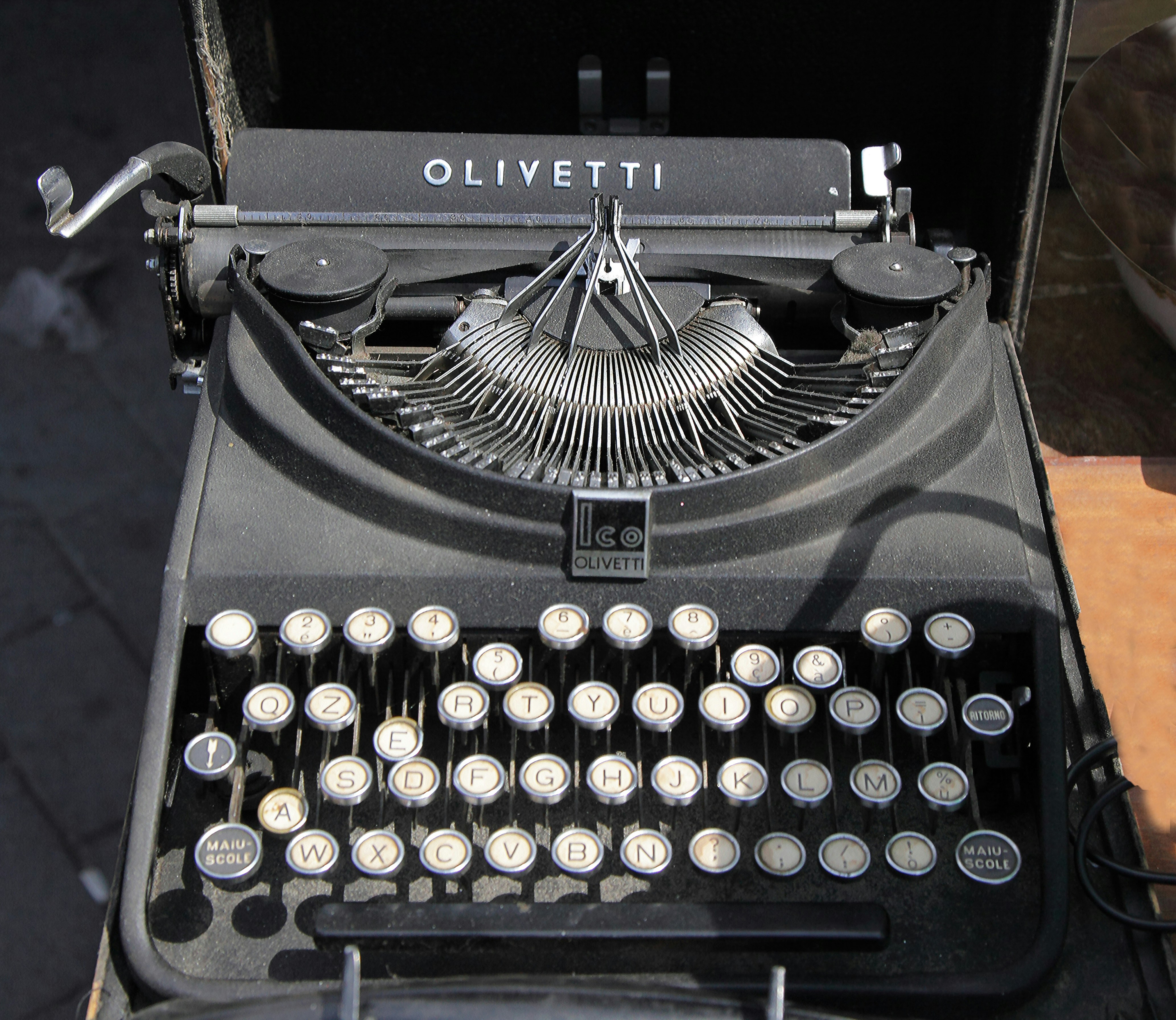 Una vecchia macchina da scrivere nera Olivetti con tasti bianchi.