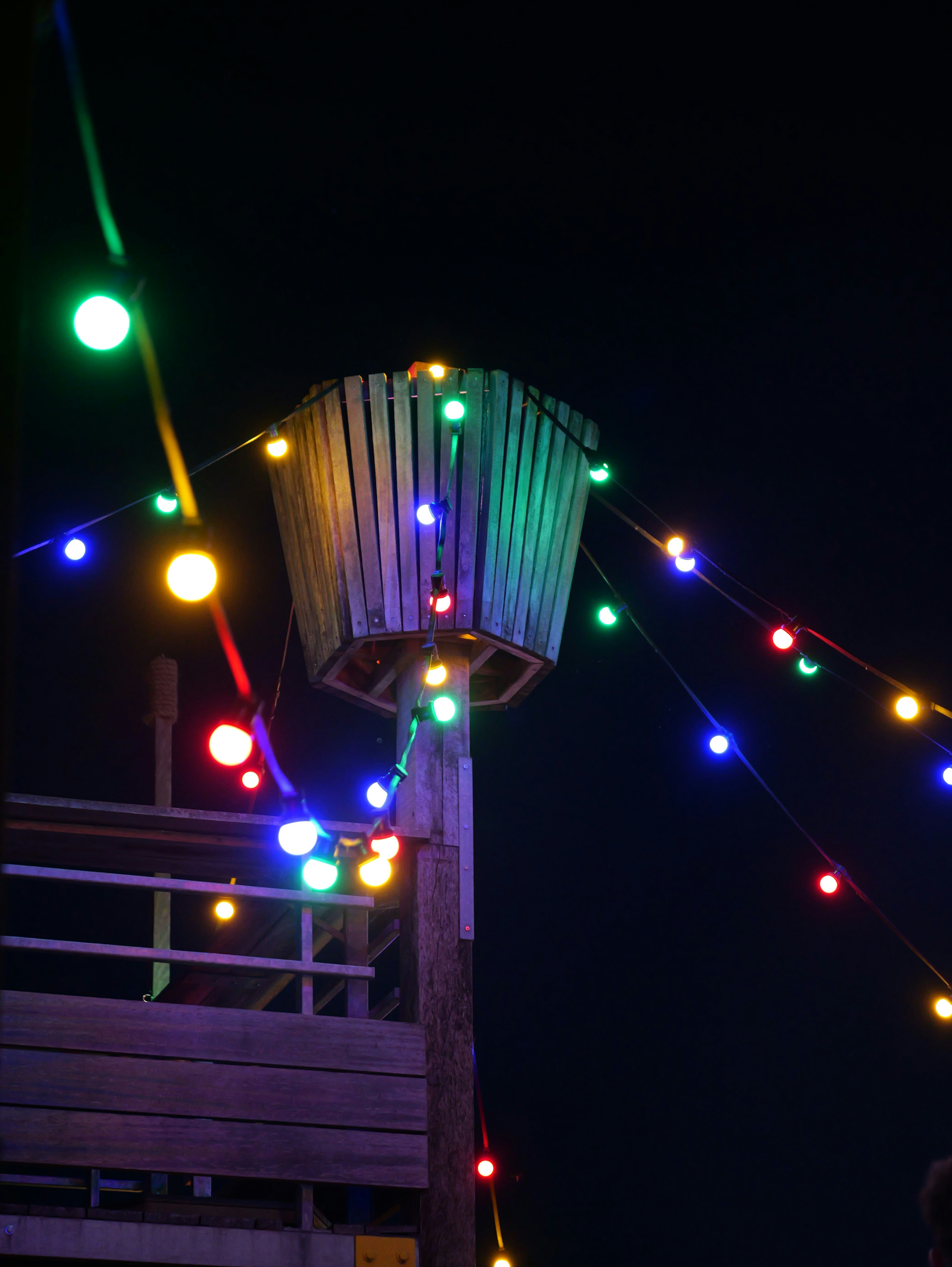 カラフルなストリングライトが夜になると木造の建物を照らします。
