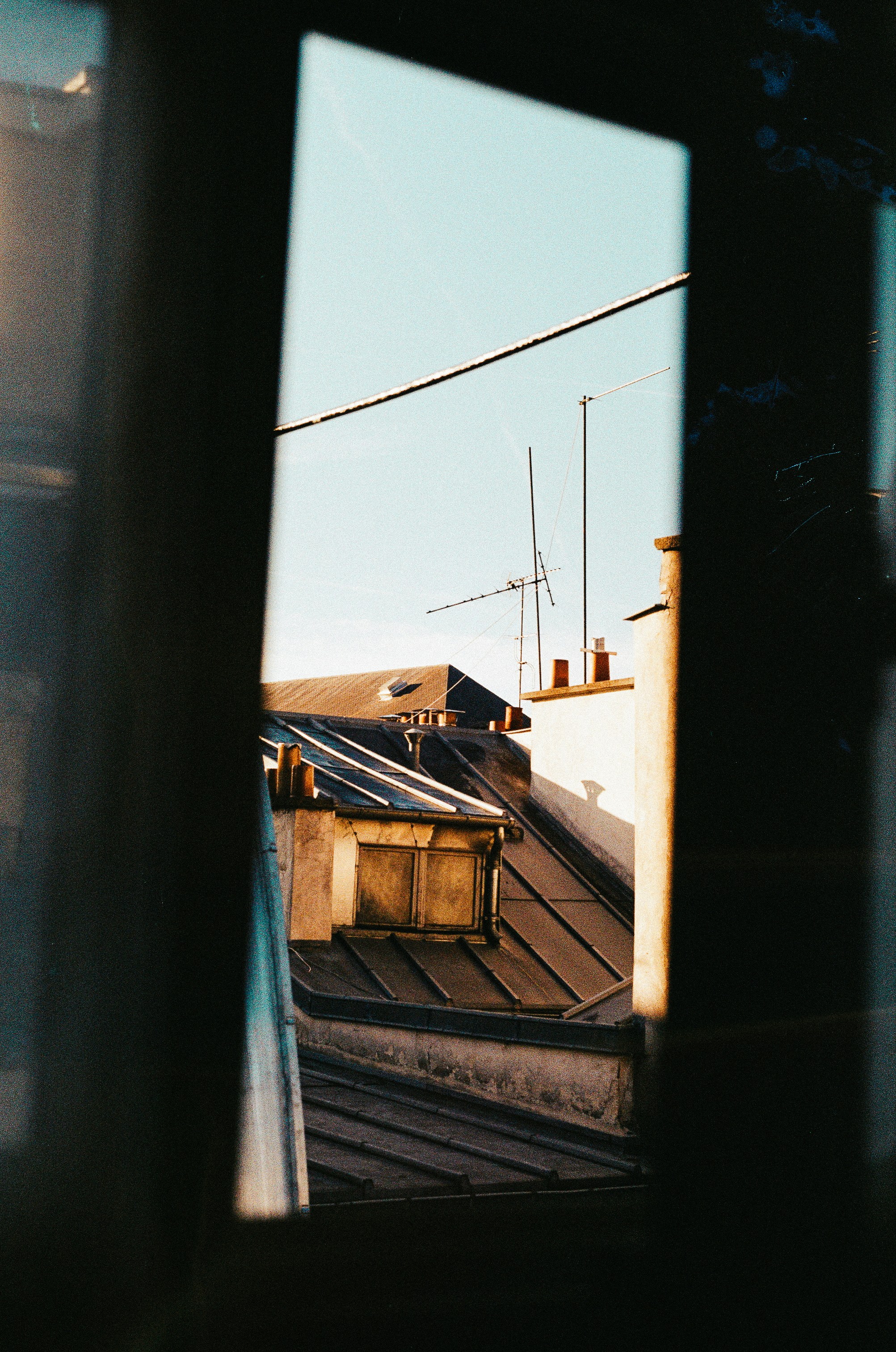 Sonnenlicht beleuchtet Stadtdächer und Antennen durch ein Fenster.