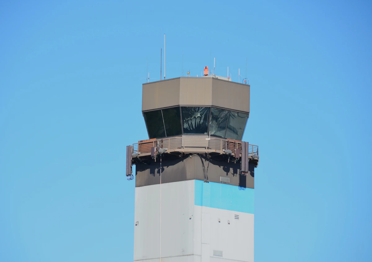 An air traffic control tower standing against a clear blue sky