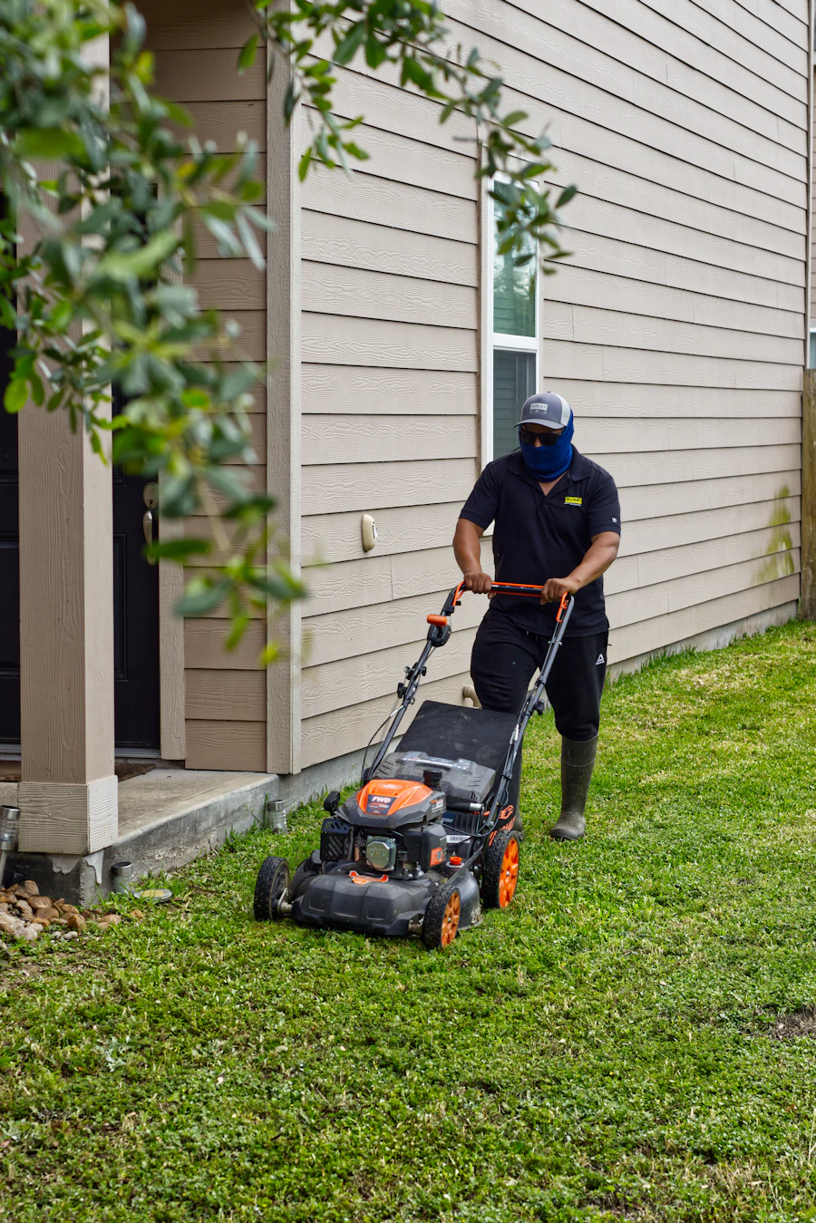 A crew member mowing alongside a grey house