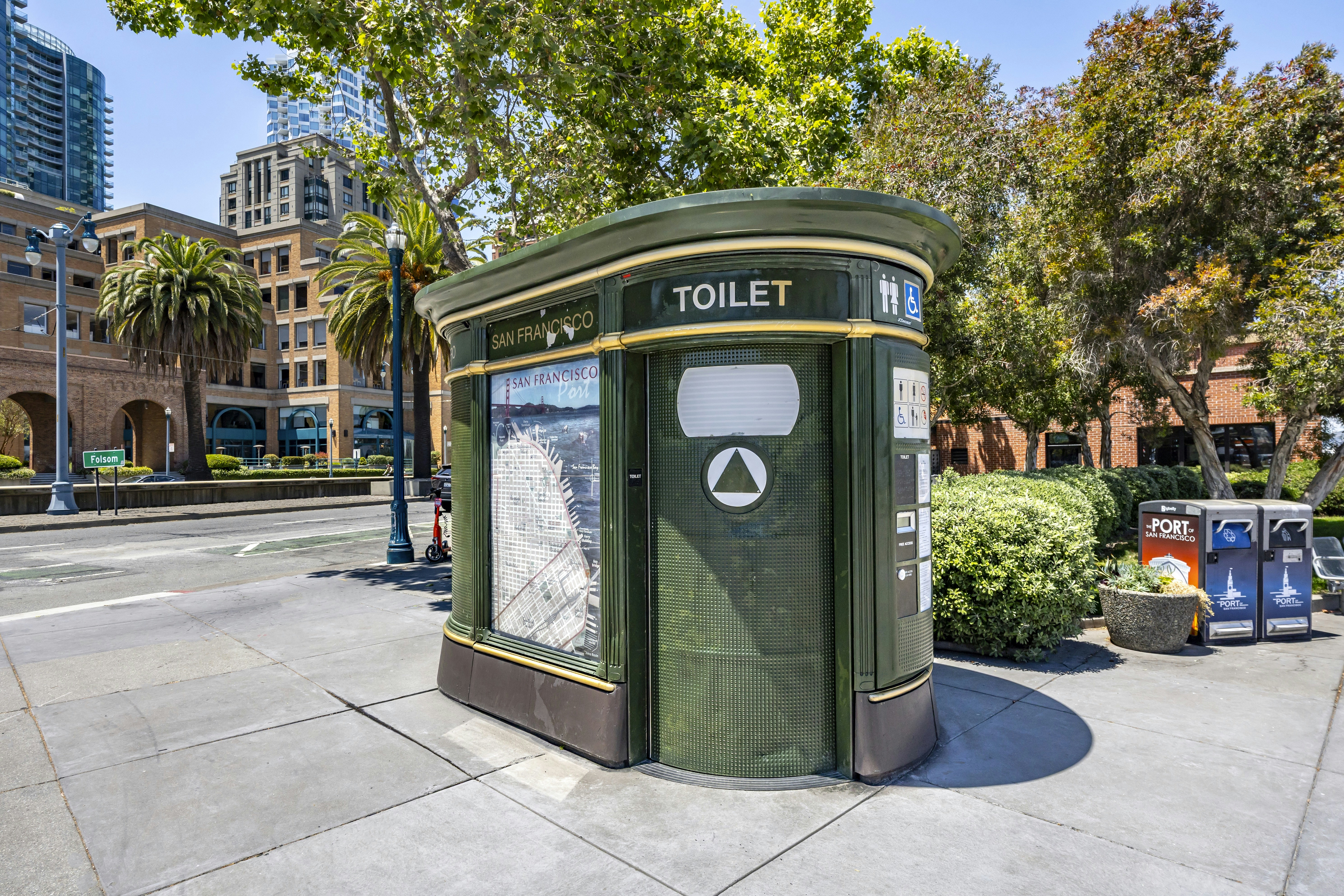Toilettes publiques vertes sur un trottoir de la ville.