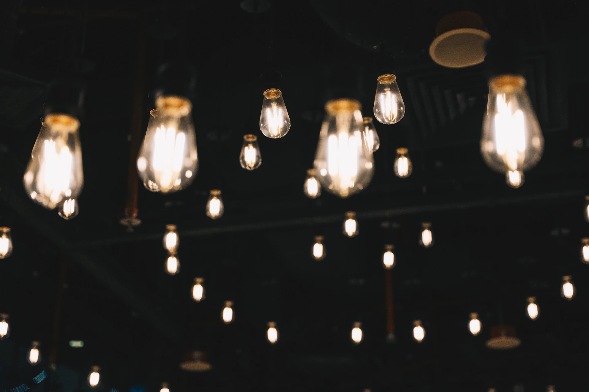 Many glowing light bulbs hanging in a dark room