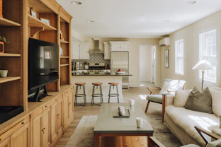 Spacious living room and kitchen with wooden built-in shelves.