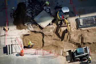 Construction site with workers, excavation, and heavy machinery
