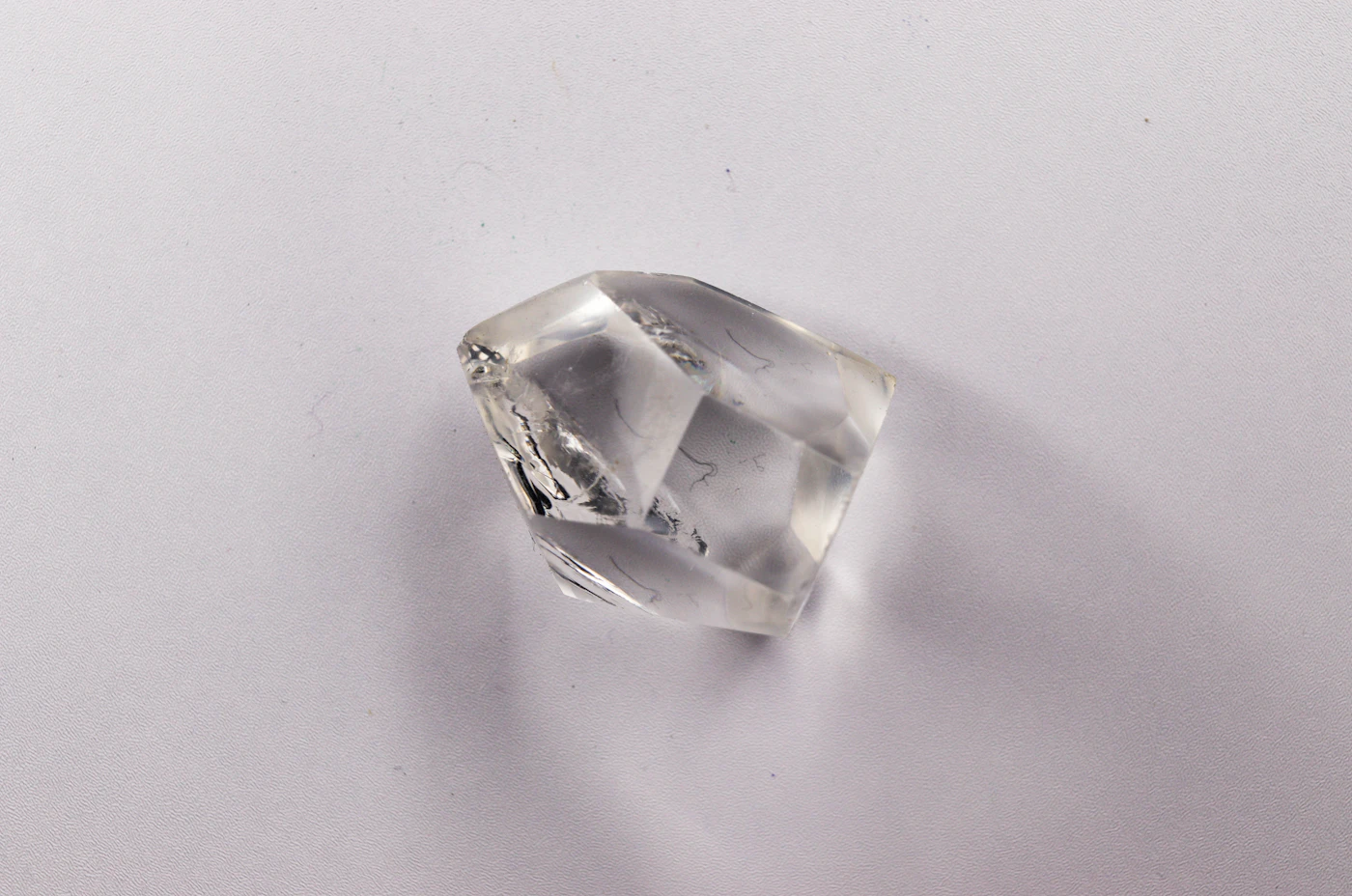 A clear, uncut rough diamond crystal on a white background
