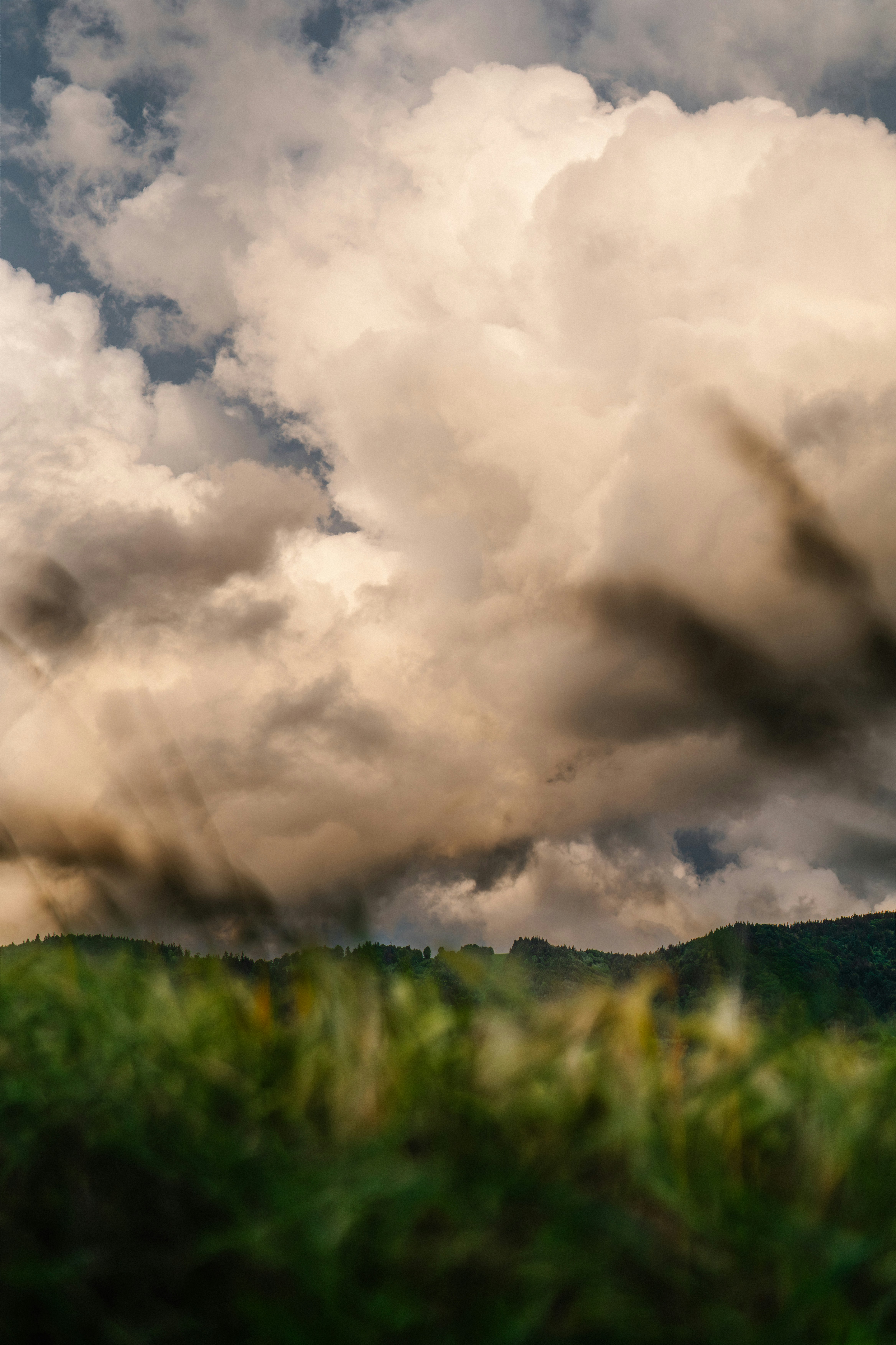 Sun rays through dramatic clouds over green hills.