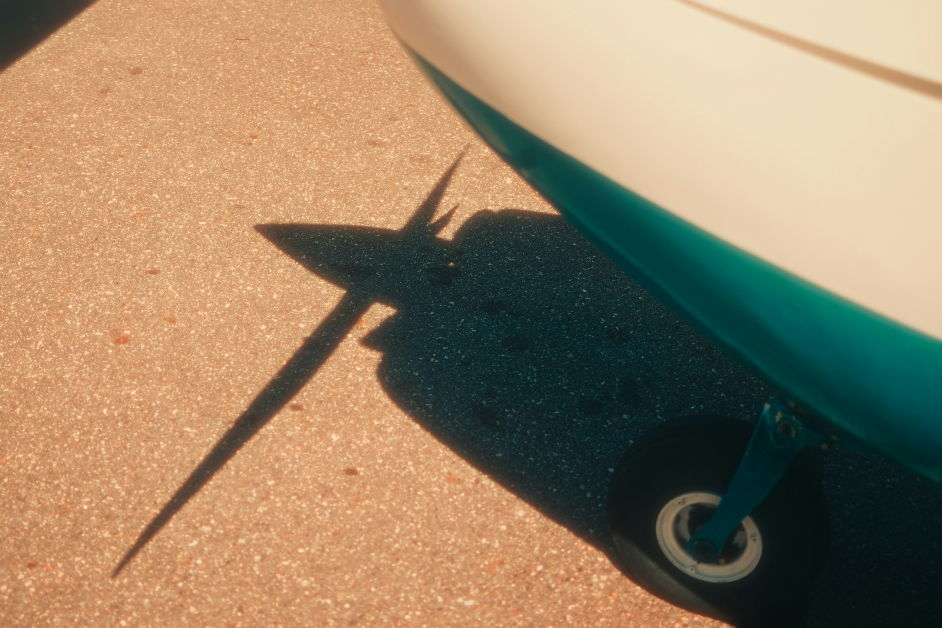 Lo scafo di una barca proietta una lunga ombra sul terreno illuminato dal sole.