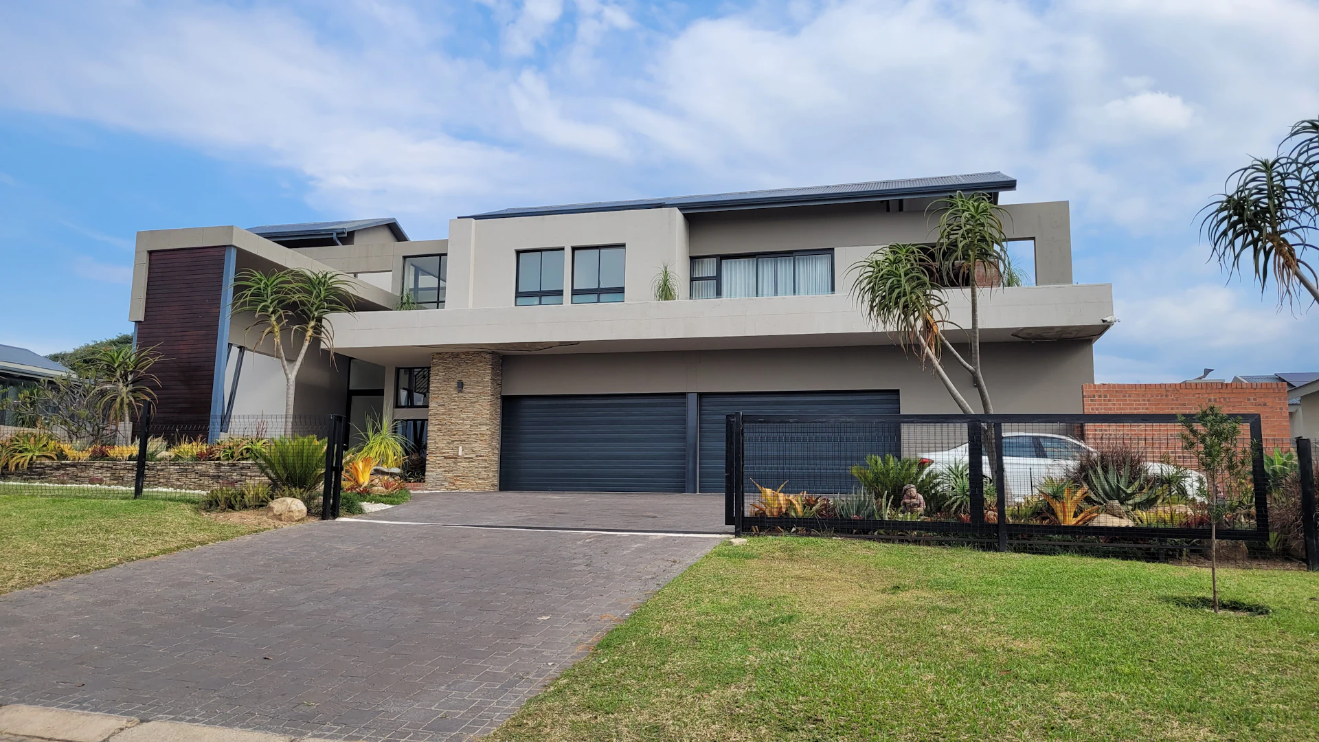 A modern two-storey home with a sunny lawn and concrete driveway